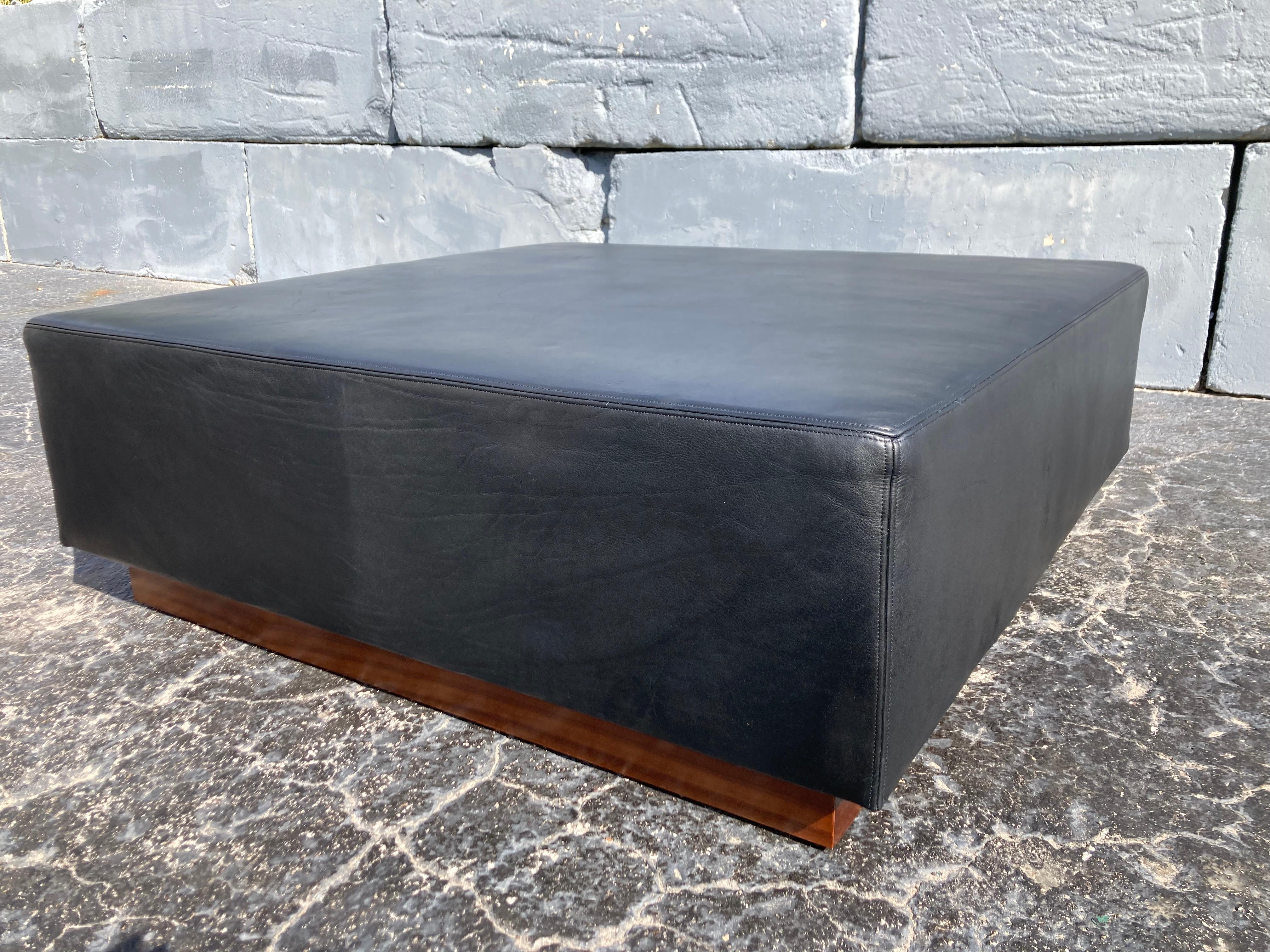 Large black leather ottoman, Mid-Century Modern style. 49” by 49” and 17.25”tall.
The black leather is beautiful with plenty of wear, walnut veneered base. Great for a home or store.
 