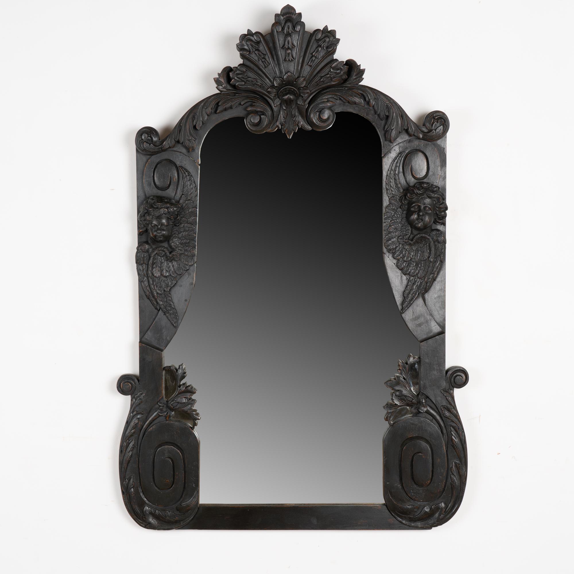 Large and impressive carved oak mirror with cherub/putti faces with wings in addition to other elaborate carved flourishes throughout. 
This mirror is just under 6' tall and has been given a newer custom black painted finish, gently rubbed out to