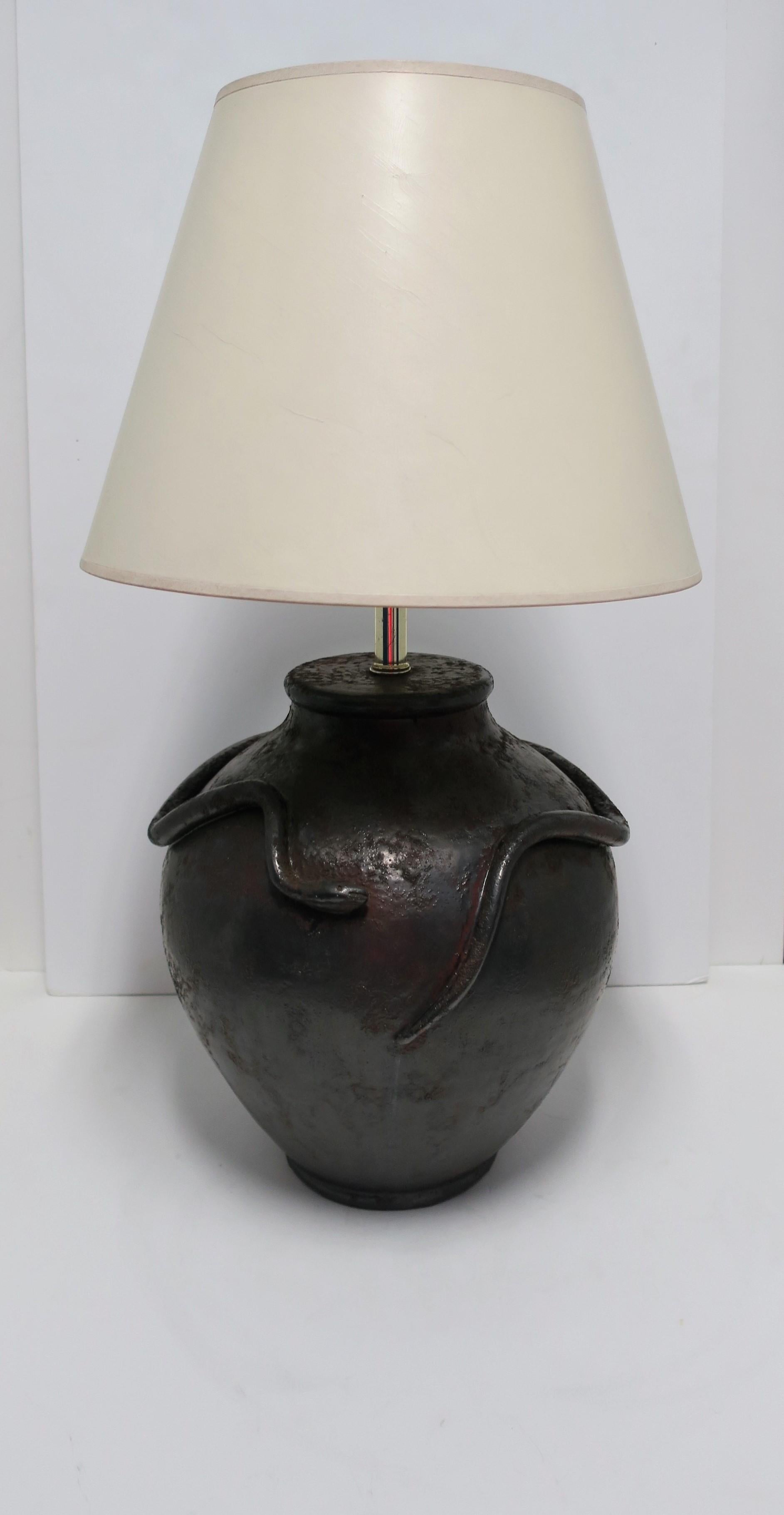 A relatively large black textured pottery lamp with 'snake and basket' design, circa 1970s. Lamp, in basket form, has a textured surface with a touch of a 'terracotta' hue. Raised snake relief winds around. 

Lamp measures: 
21.5