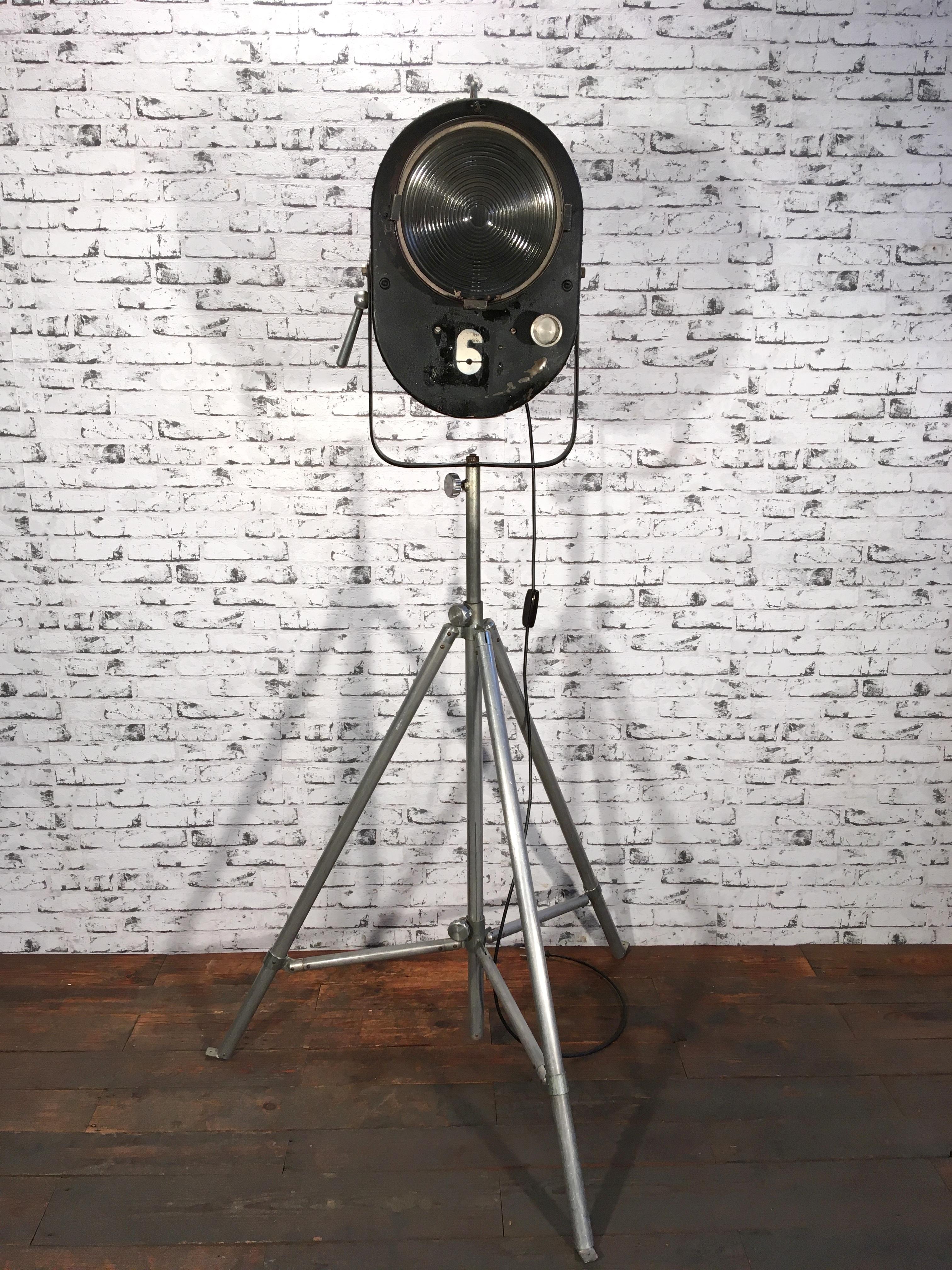 This large adjustable theater reflector on aluminium tripod comes from former Czechoslovakia. It was made during the 1950s. The spotlight has a black metal body and features clear glass. It is fitted with an E 27 socket. Fully functional. Good