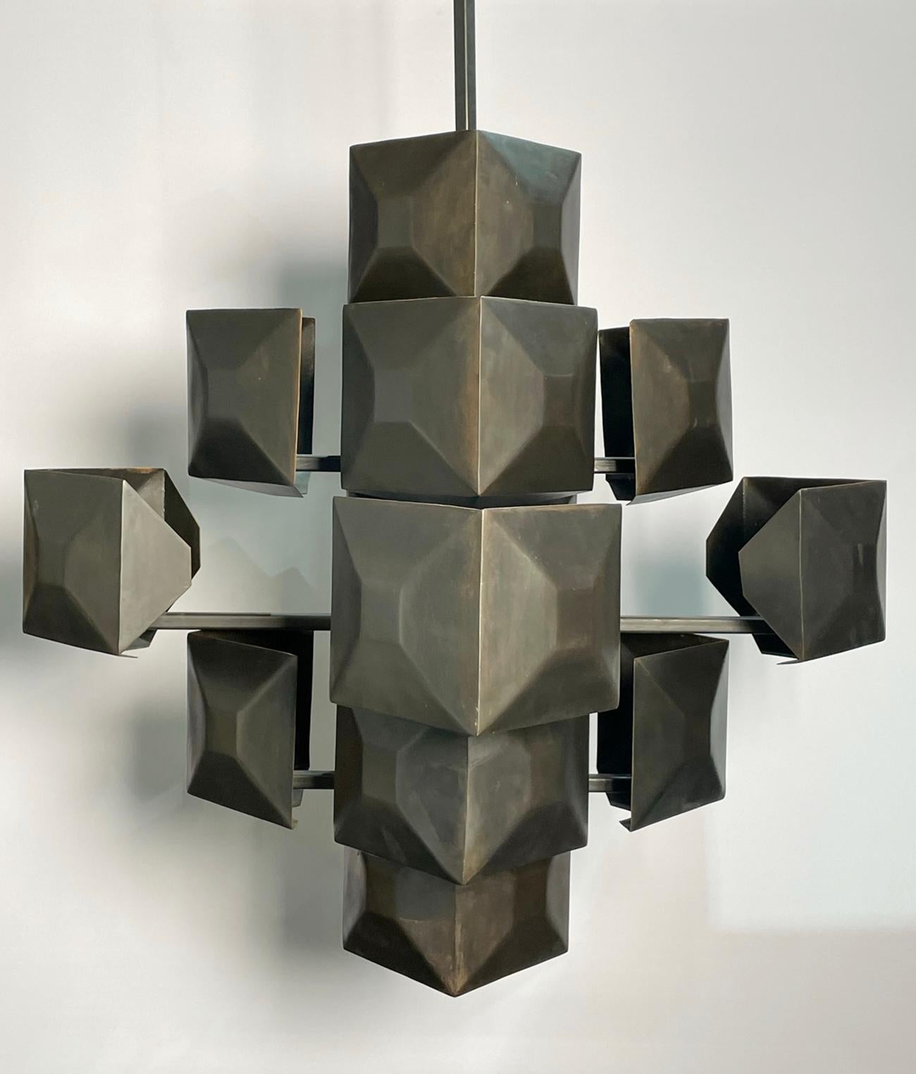 Introducing the Large Blackened Steel Chandelier, expertly crafted in the USA by the renowned artisans at Blackman Cruz. This stunning metal sculpture features an abstract design composed of multiple cubes and squares, creating a unique and