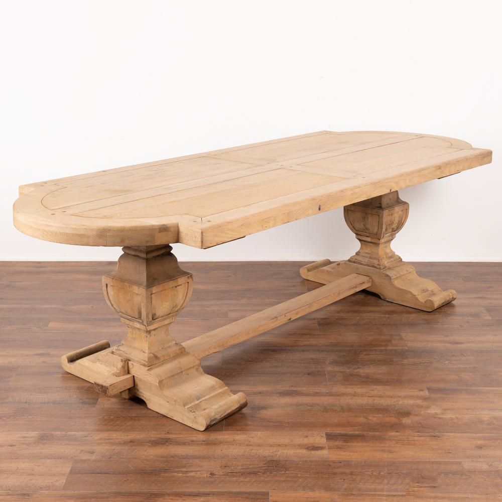 Large bleached oak dining table from France with impressive carved trestle base and thick top.
The original dark oak has been bleached, creating a fresh, lighter look for today's modern home. 
The decorative curved ends allow ample seating space
