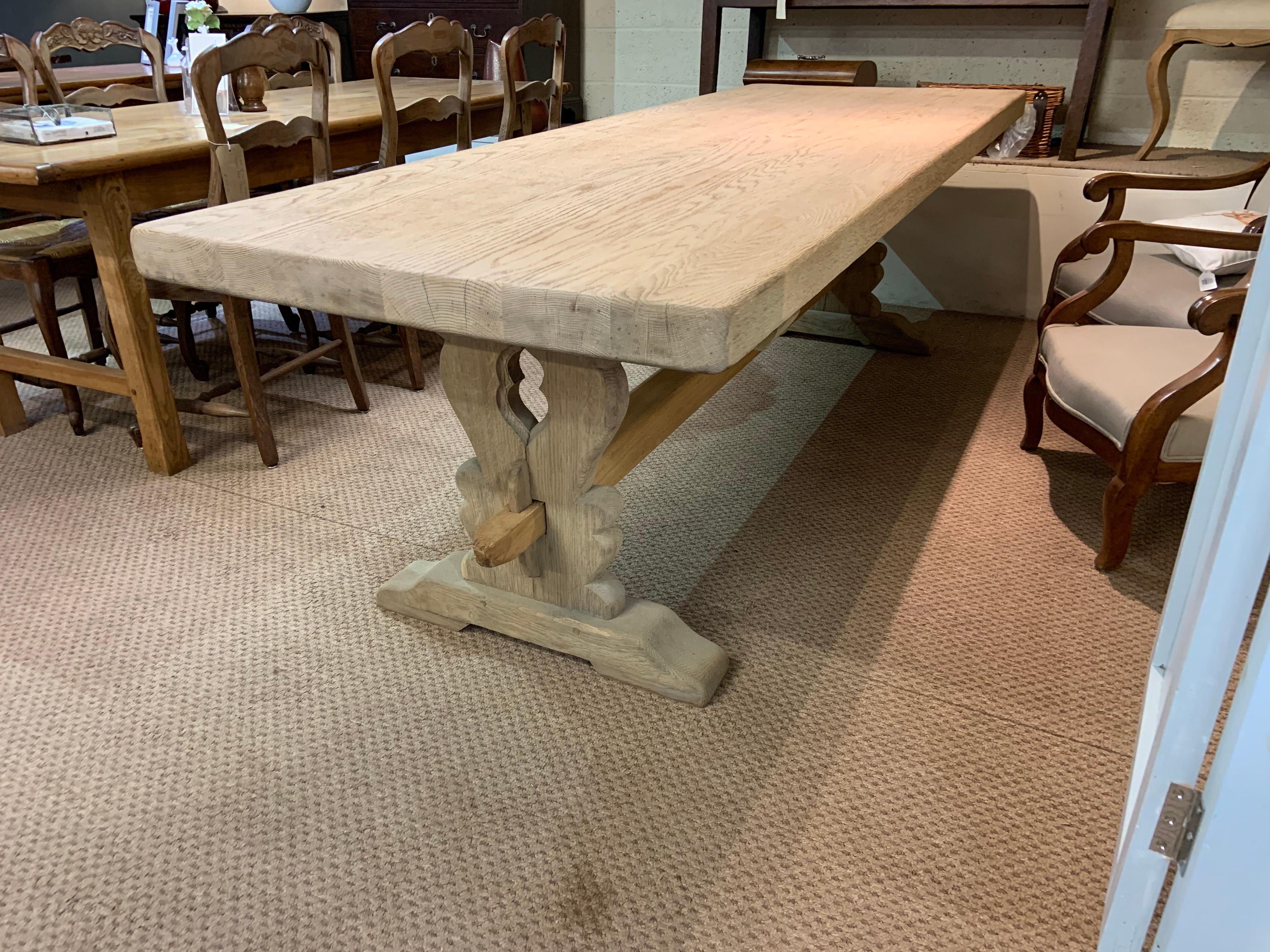 Large bleached oak farmhouse table with trestle style base. Table has a thick top with sturdy trestle supported by a centre stretcher.