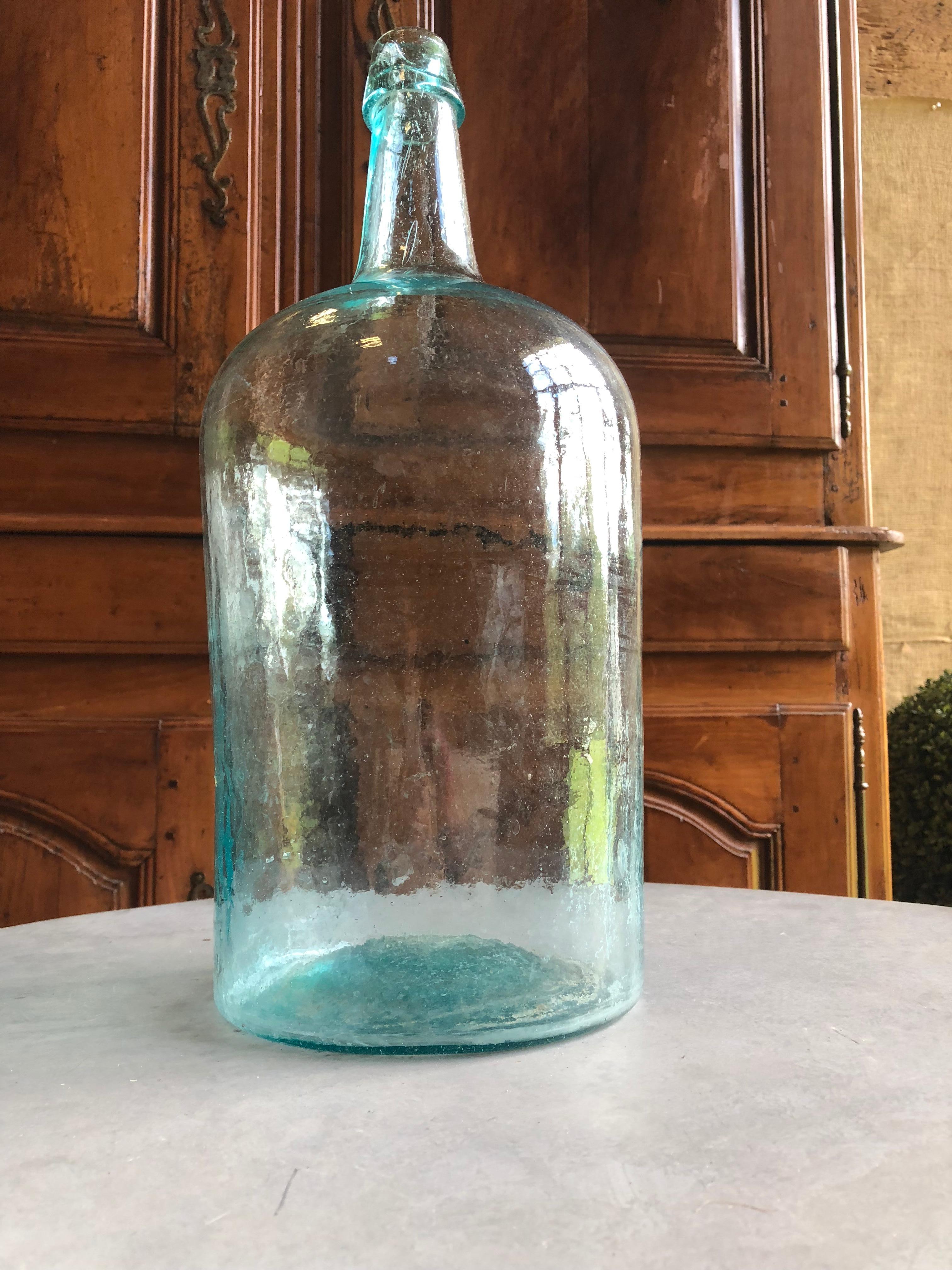 A large aqua blown glass bottle wine h straight sides and an applied lip, probably French 19th century, with surface ripples and seed bubbles throughout.