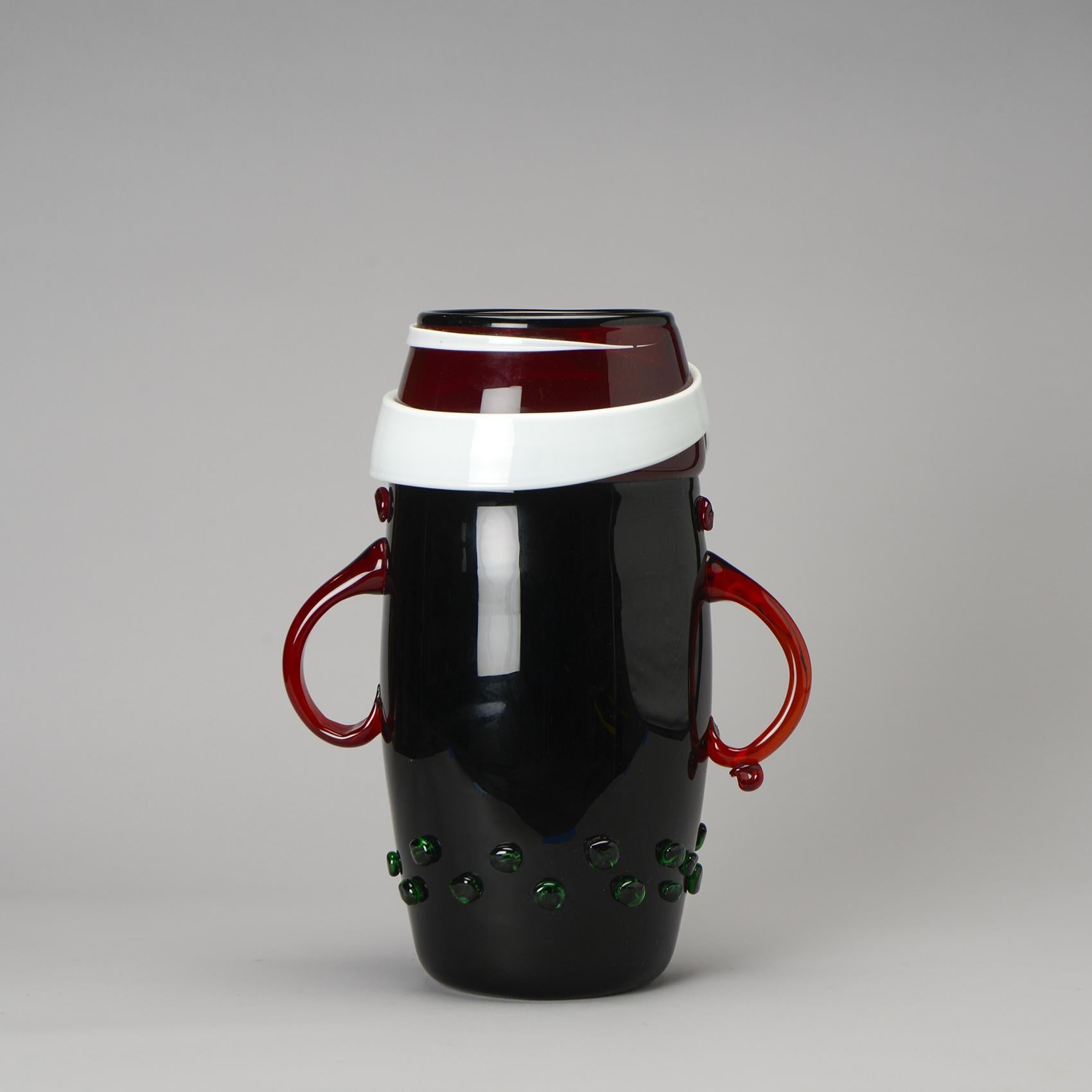 More than a simple decorative item, the grand vase model 8962 by Izzika GAON is a veritable work of art.

Crafted from blown polychrome glass, its oblong shape showcases a captivating design adorned with  green button appliques and two striking red