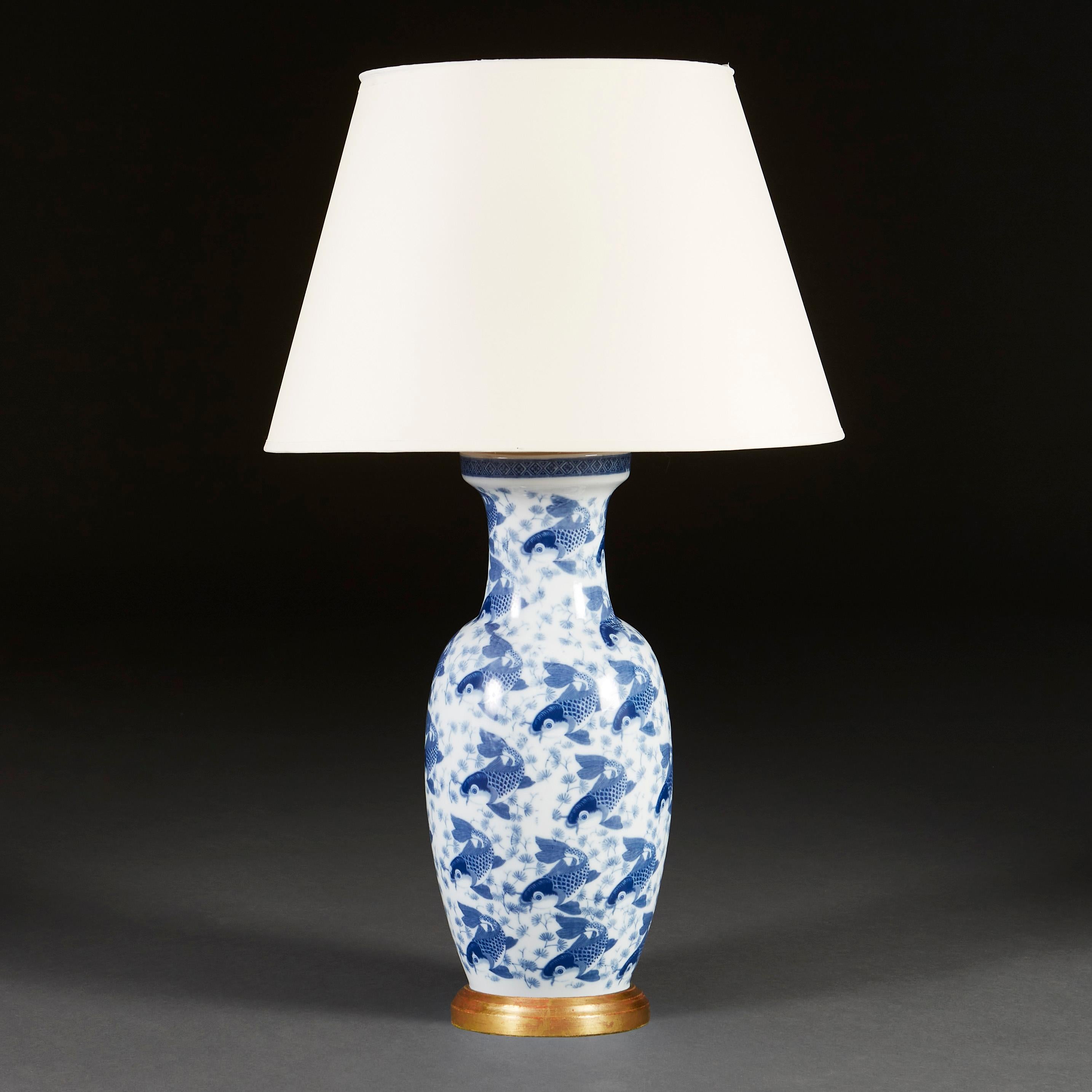 A mid twentieth century blue and white vase of large scale, decorated with swimming carp throughout, now converted as a lamp with a turned giltwood base.

Please note: Lampshade is not included.
Currently wired for the UK with patinated brass plate