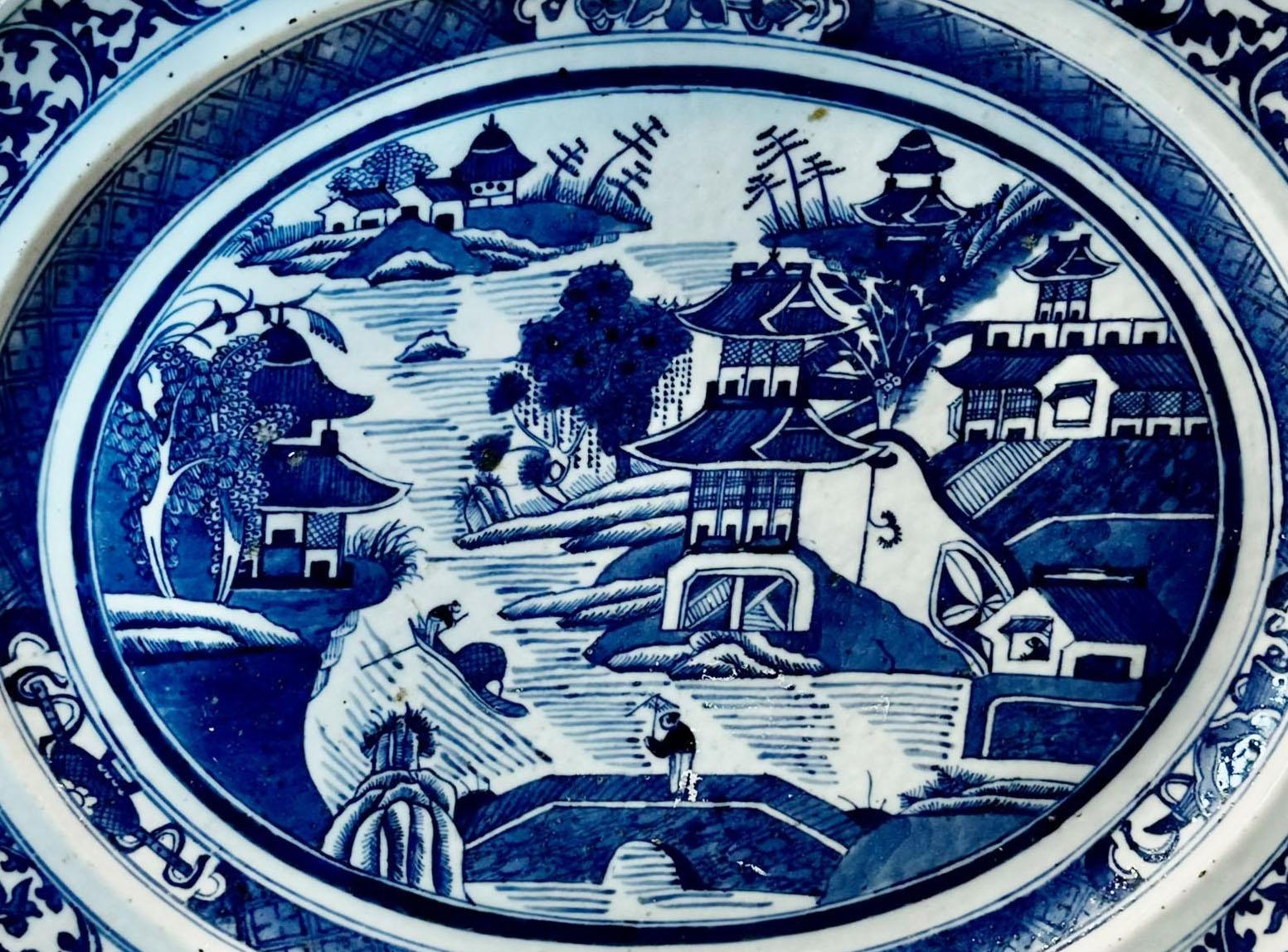 Plat de canton chinois du XVIIIe siècle en bleu et blanc classique. Il s'agit d'un très beau plateau représentant la vie d'un village avec une dame traversant un pont et un homme ramant sur un bateau. La surface de la porcelaine présente un aspect