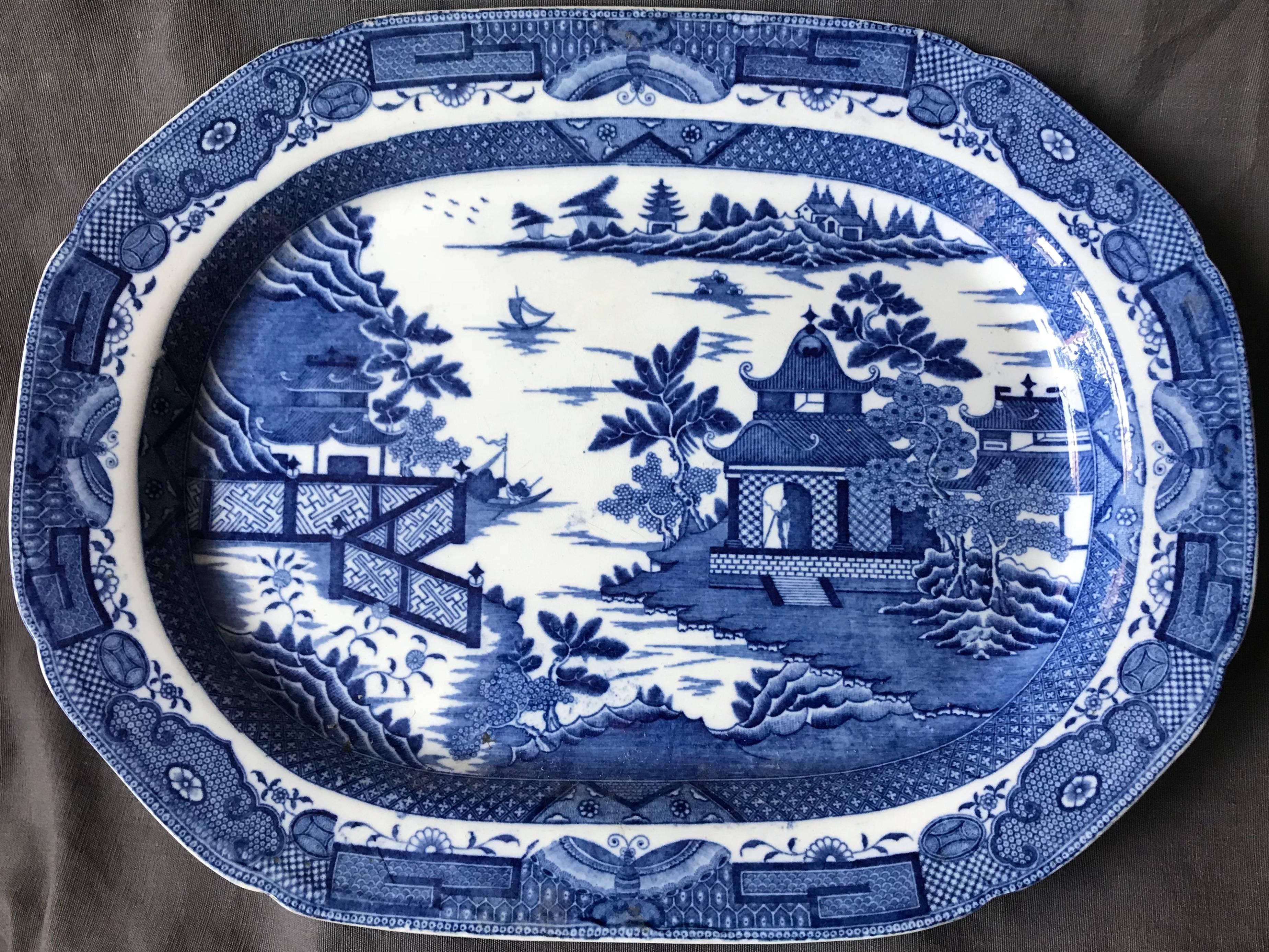 Large blue and white chinoiserie platter. Large Davenport platter with rich blue border of butterflies framing pagoda in a lagoon with fretwork fencing and figures. England, mid-19th century.
Dimensions: 16.88