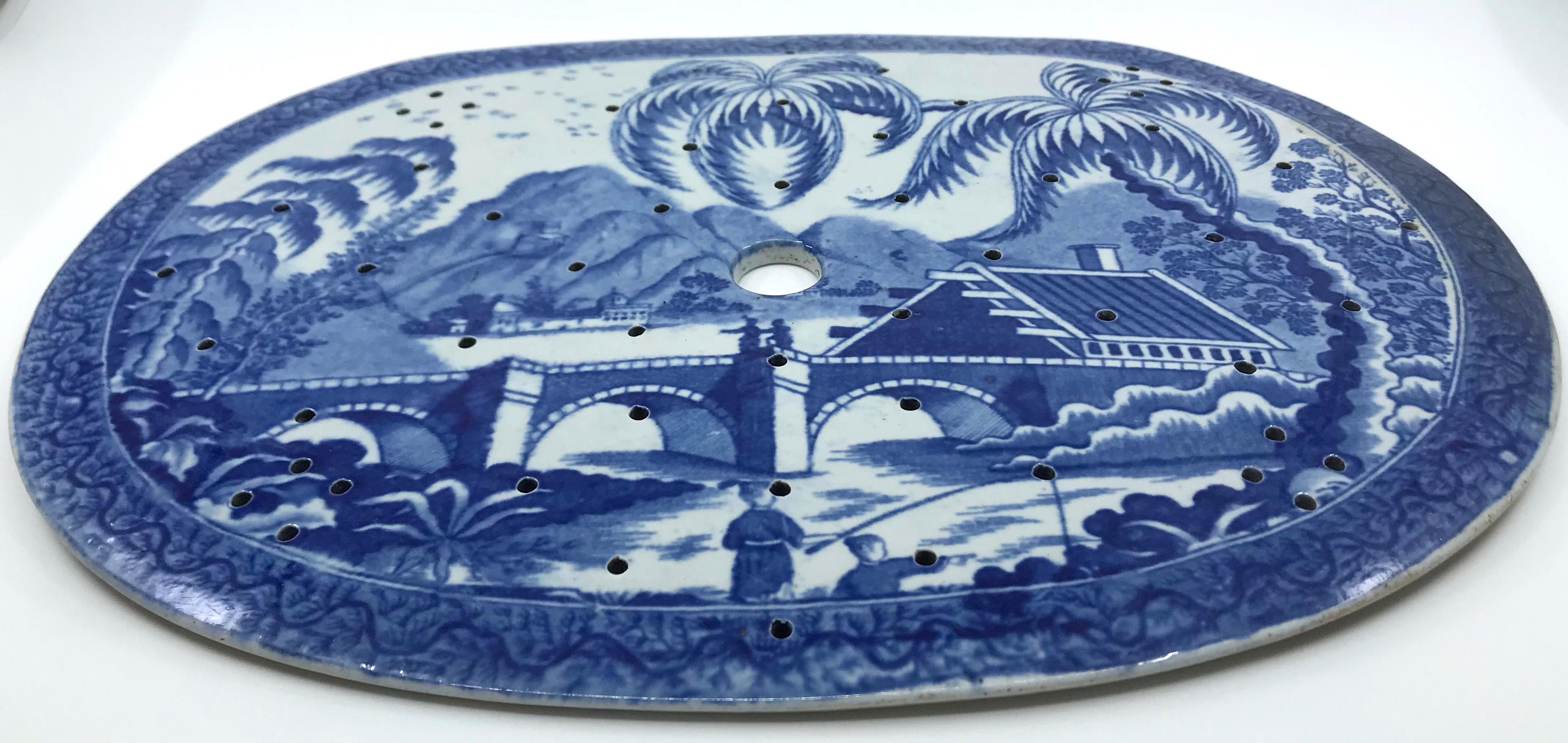 Large blue and white chinoiserie strainer. Substantial and rare early Worcester strainer with strong blue and white chinoiserie scene with figures on covered bridge with large palm trees and mountains in distance all framed by blue banded rim.