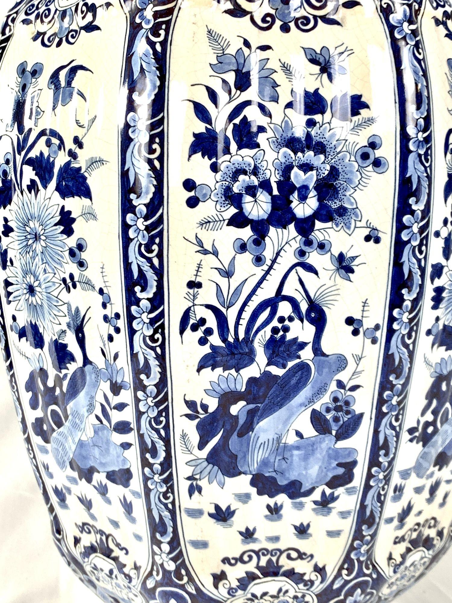 This large Delft jar has a traditional bird and flower decoration painted on a white tin-glazed ground. 
The decoration captures the beauty of a garden with birds amidst a sea of vibrant flowers. 
The design on the shoulders and cover is a classic