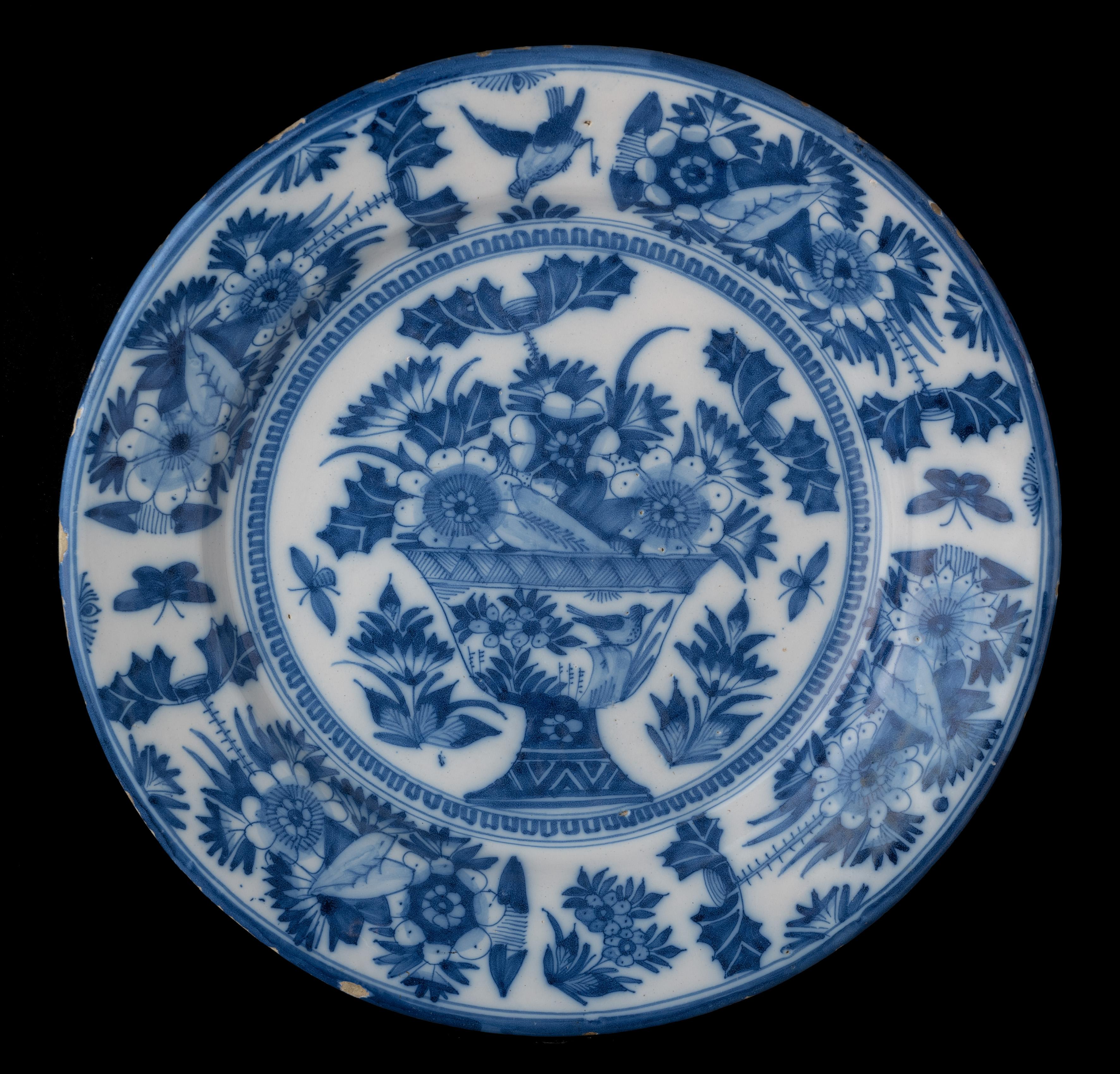 Blue and white dish with flower vase. Delft, 1665-1675
The blue and white dish has a wide, spreading rim and is painted in the centre with a vase with flowers, floral sprays and butterflies. The vase itself is also decorated with flowers and a bird