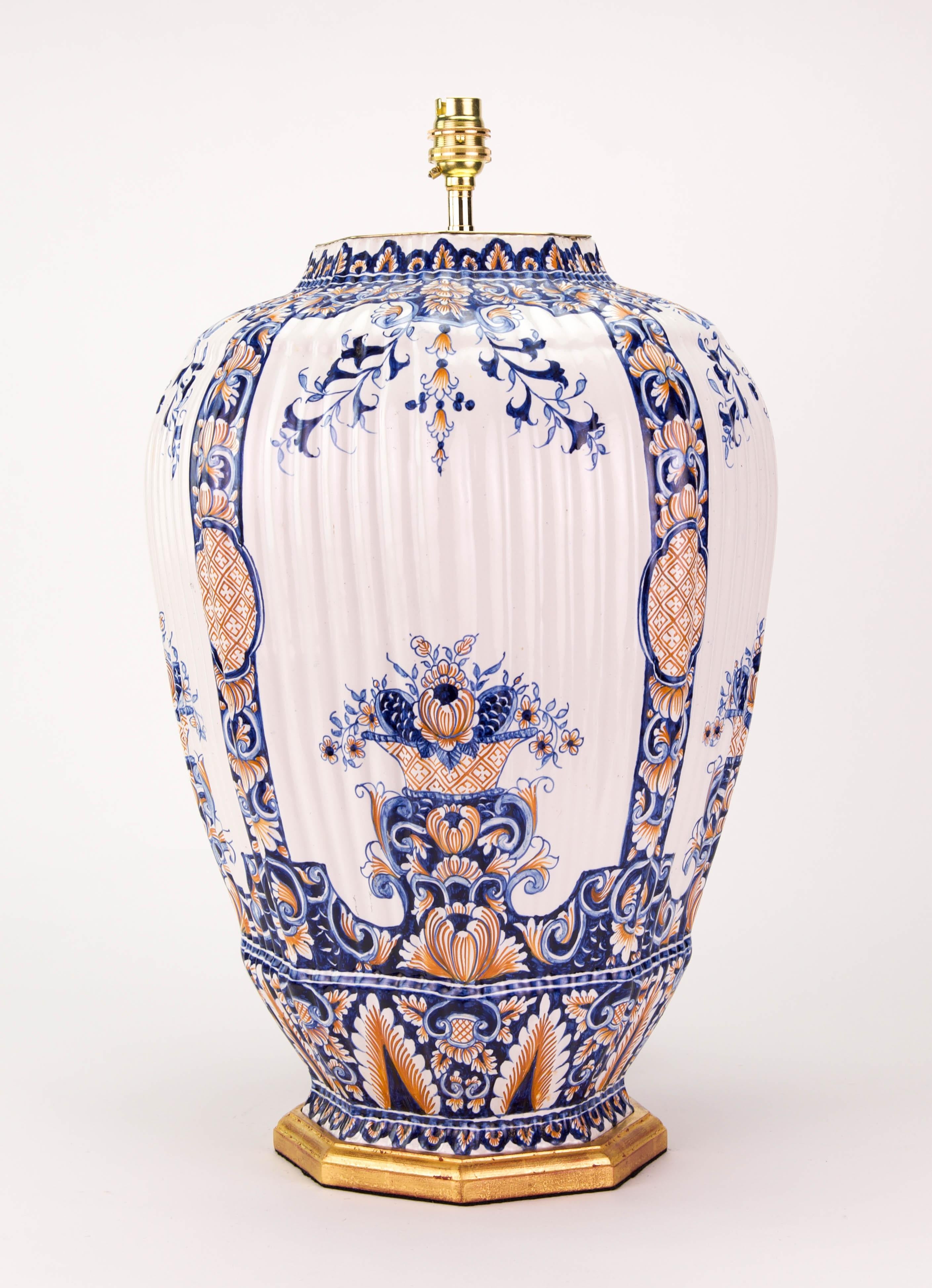 A fine large French faience vase, of hexagonal form with ribbed mouldings, and beautifully decorated in tones of blue and red on a predominantly white ground, with stylised foliage and flowers throughout, now mounted as a lamp with a giltwood