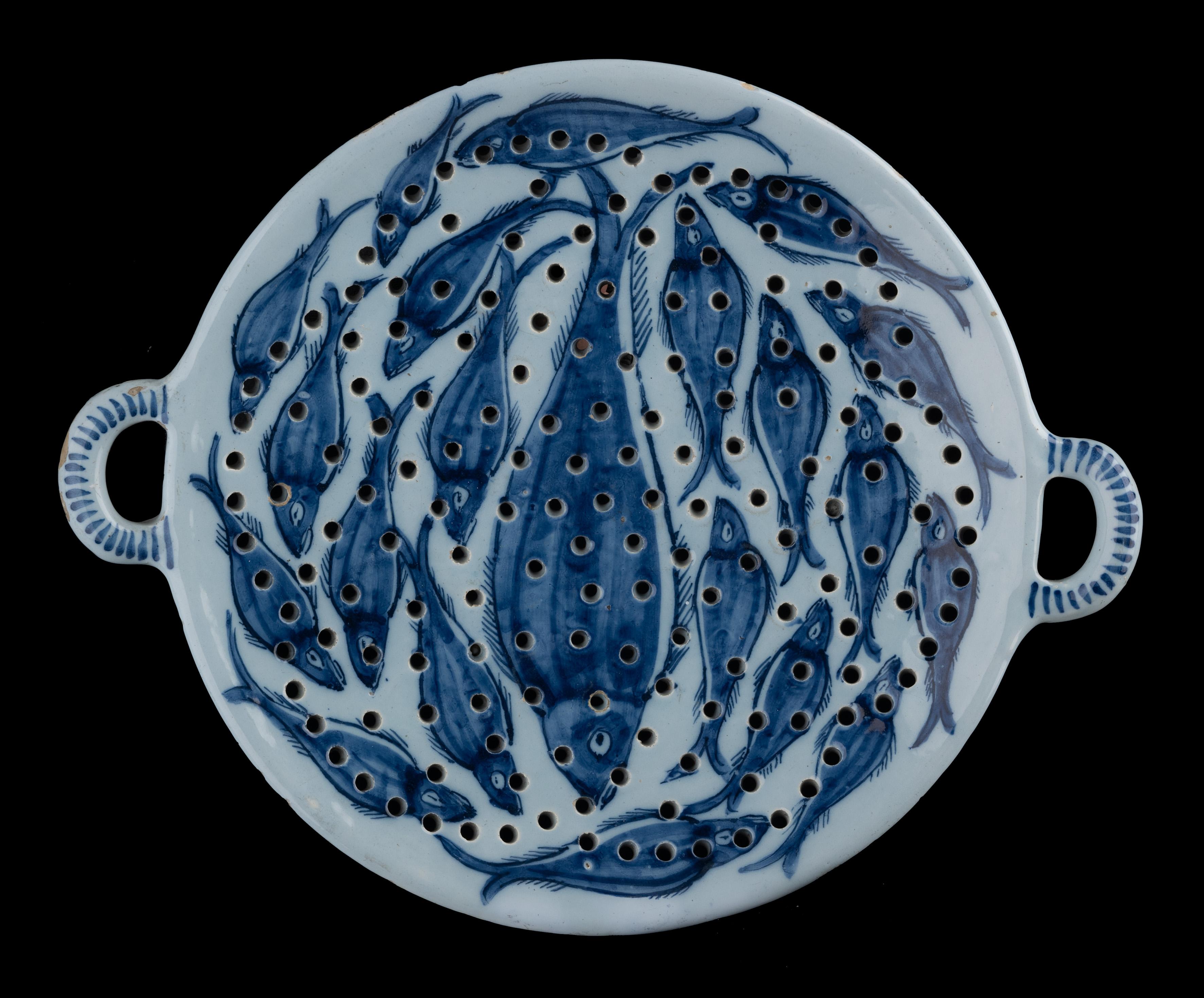 Blue and white fish colander Delft, 1725-1750

The blue and white colander stands on three legs and has two round handles. Painted on the front are one large and twenty small fish, presumably bream. The back features an exuberant floral design,