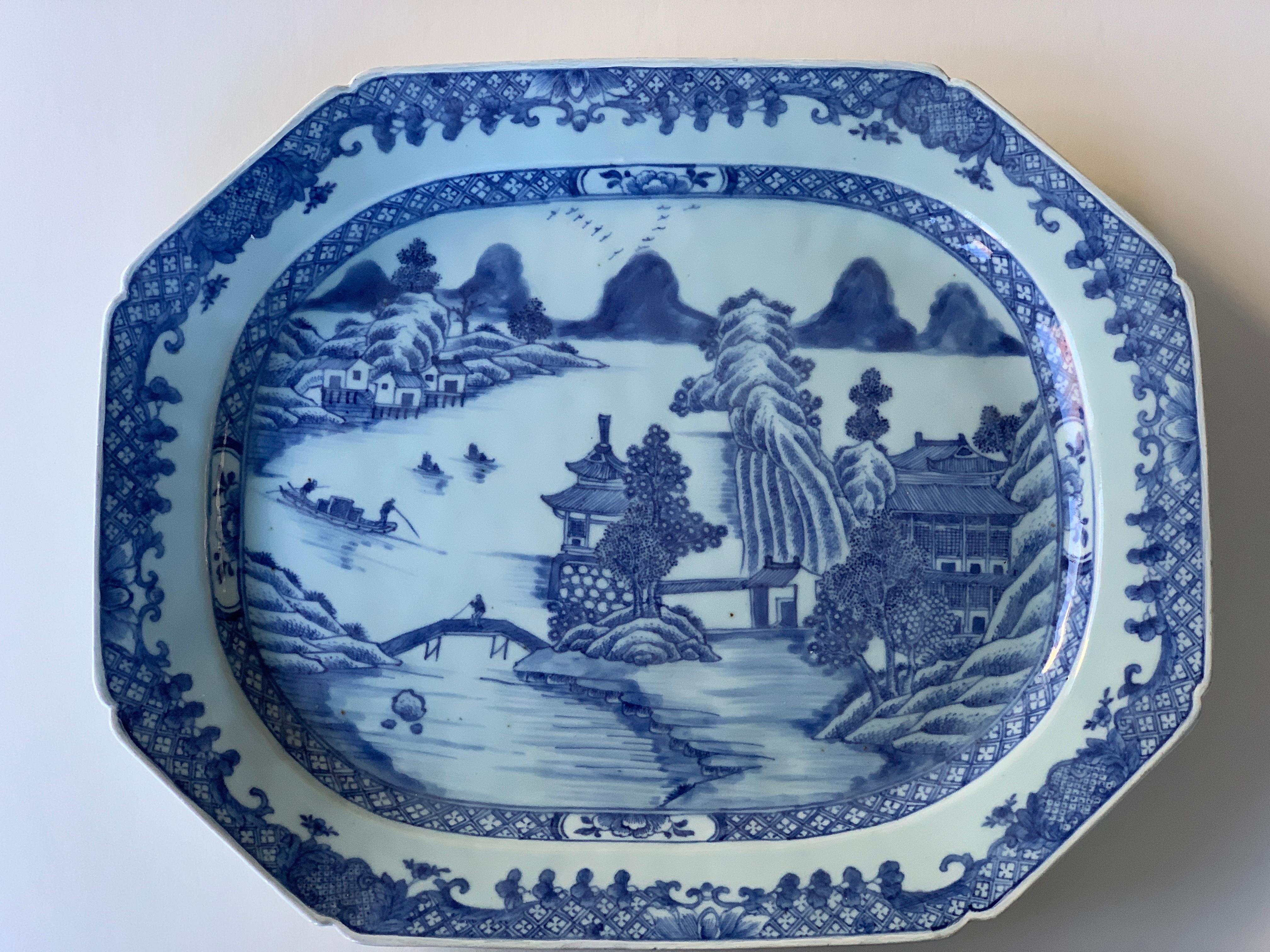 This large hand-painted blue and white Chinese porcelain platter was made in the 18th century, Qianlong period, circa 1780. 
The scene shows a harbor with flower-filled trees, pagodas, rockwork, and distant mountains. Small details add to the