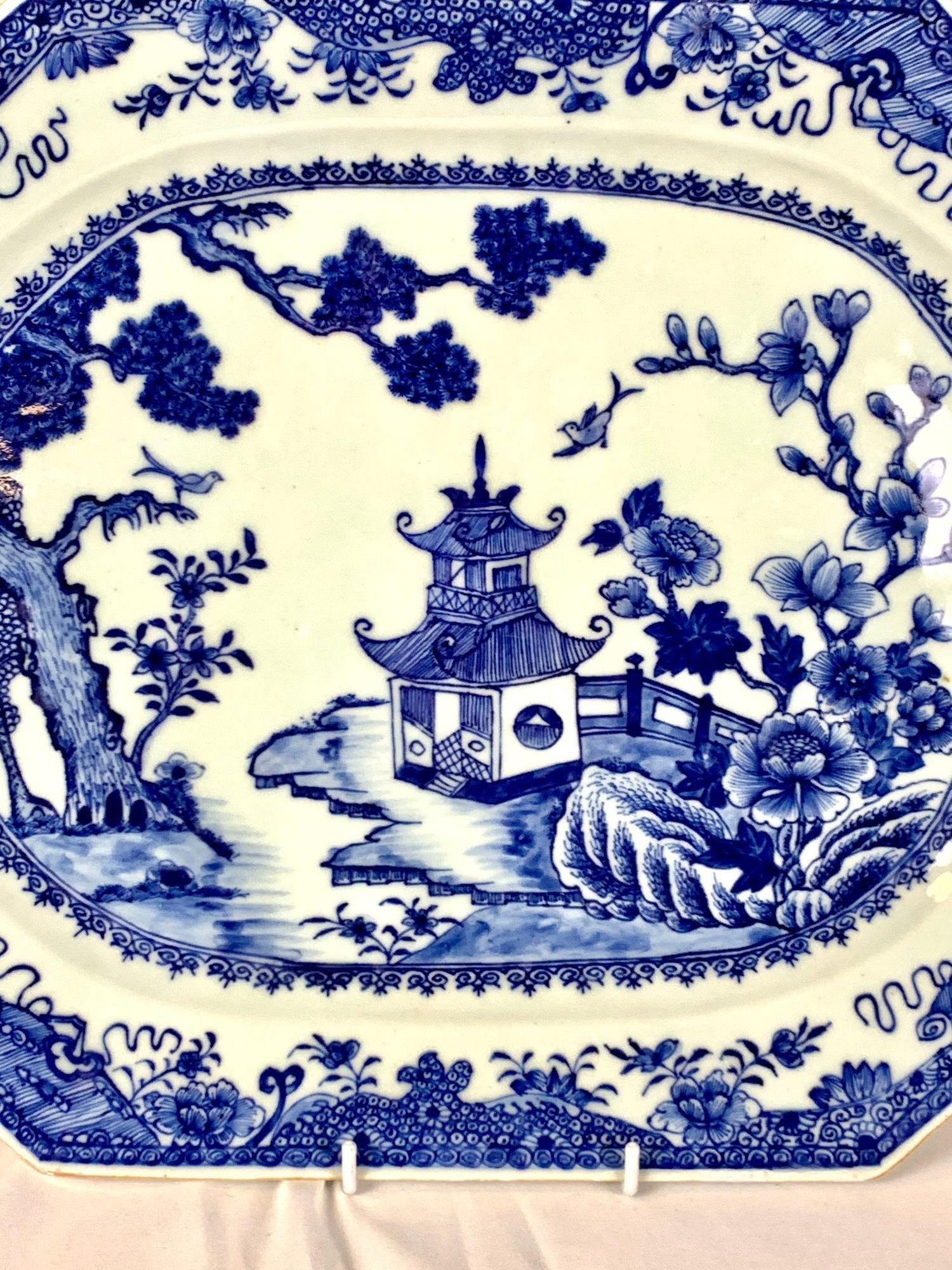 This large Chinese porcelain platter was hand-painted in cobalt blue during the Qianlong period, circa 1780.
The platter depicts a beautiful seaside landscape with a pagoda, garden fence, rockwork, and three trees known as the Three Friends of