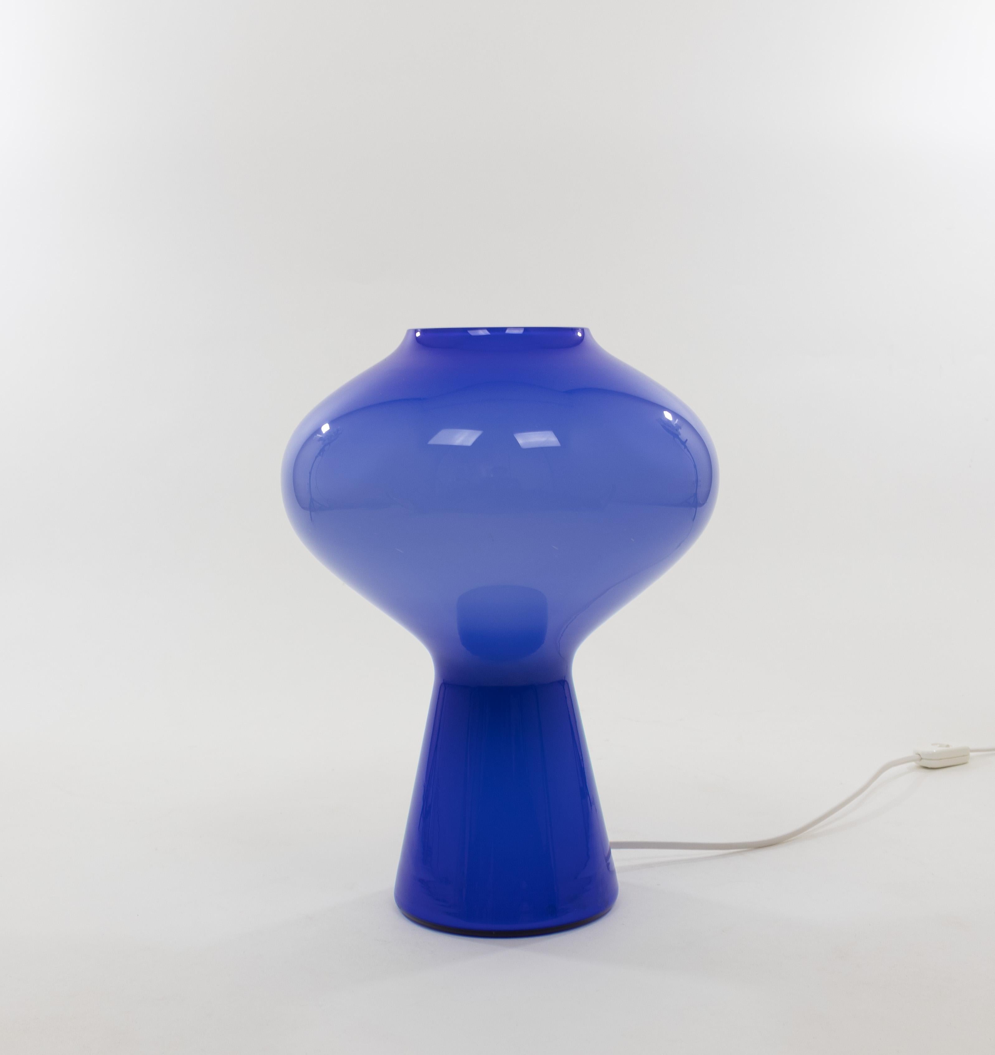 Lámpara de sobremesa Fungo de cristal soplado azul, diseñada por Massimo Vignelli al comienzo de su impresionante carrera en el diseño y ejecutada por Venini, especialista en cristal de Murano. Este es el tamaño más grande de la serie Fungo.

La