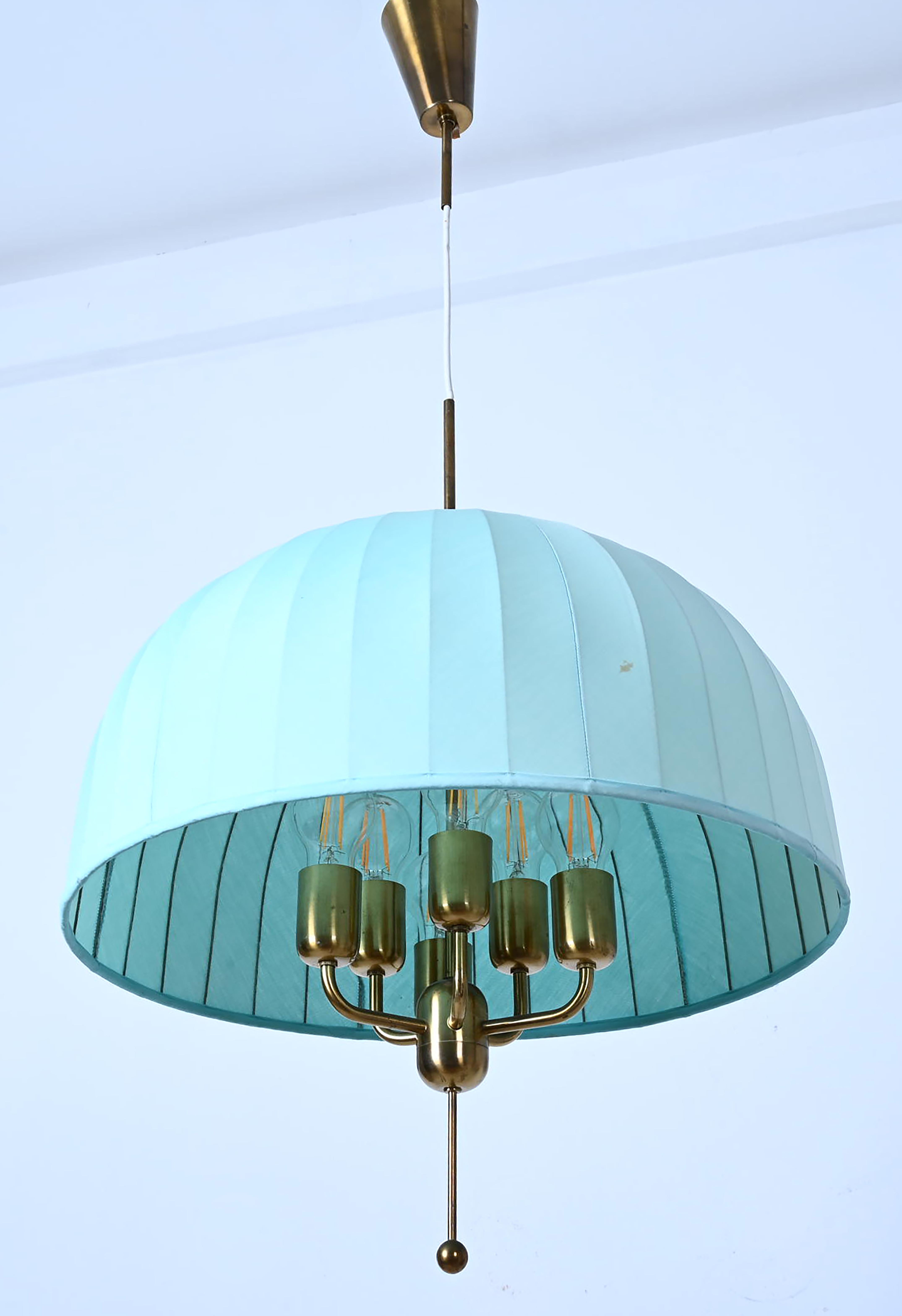 Raro grande pendente da soffitto con paralume in tessuto blu su supporto in metallo. 
Modello Caroline T549/6 in ottone progettato nel 1963 da Hans-Agne Jakobsson. La lampada e il paralume sono regolabili in altezza.
6 lampadine E27.
