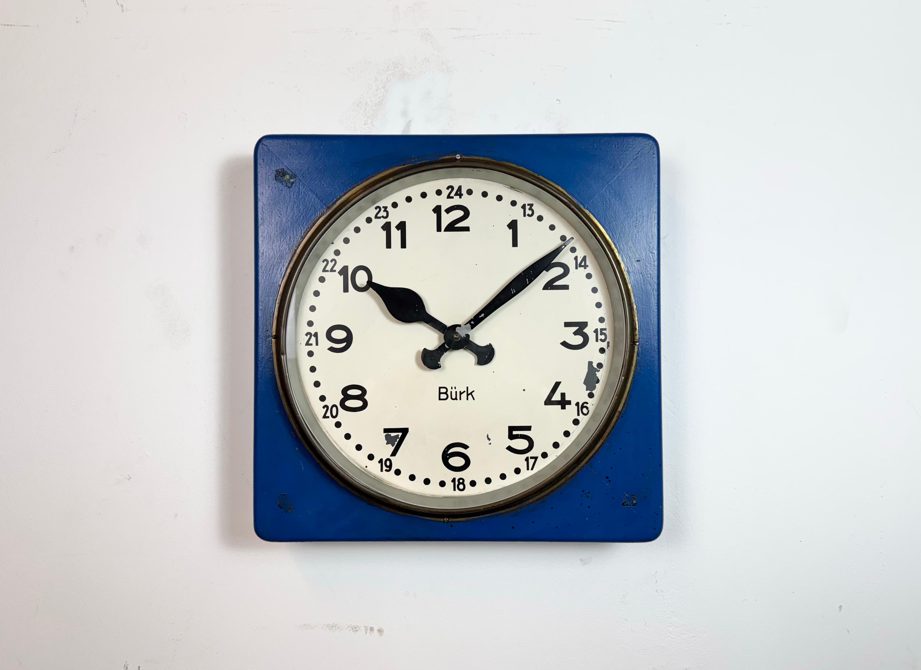 Vintage Burk wall clock was made in Germany during the 1950s. It features a blue wooden body, a metal dial, an aluminium hands and a clear glass cover with brass ring.. The piece has been converted into a battery-powered clockwork and requires only