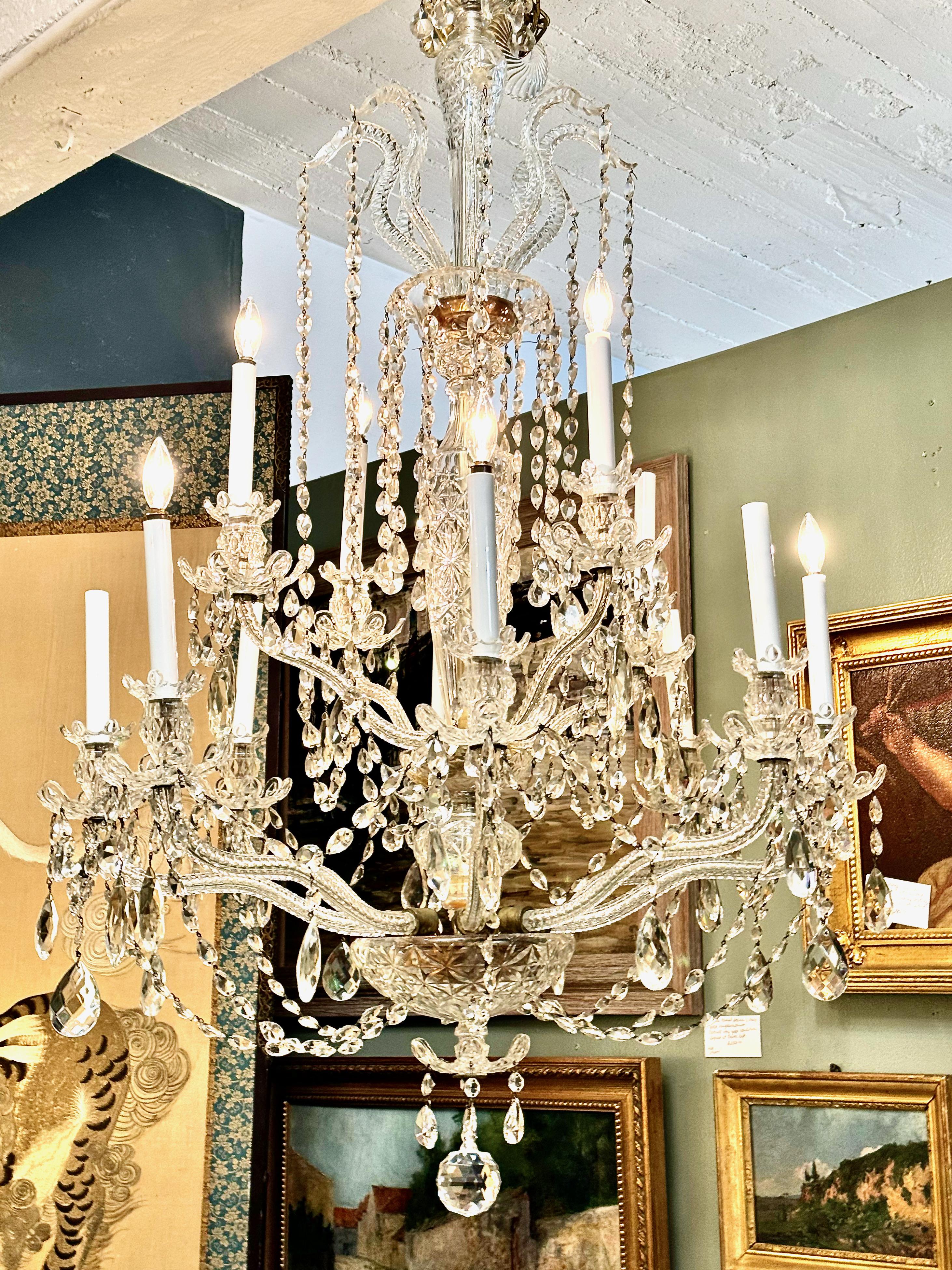 This is a large mid-20th century 12-Light Bohemian Crystal Chandelier. The photos speak to the beauty of this chandelier. The twelve cut crystal candle arms are in good condition with one arm professionally (almost invisibly) repaired some time in