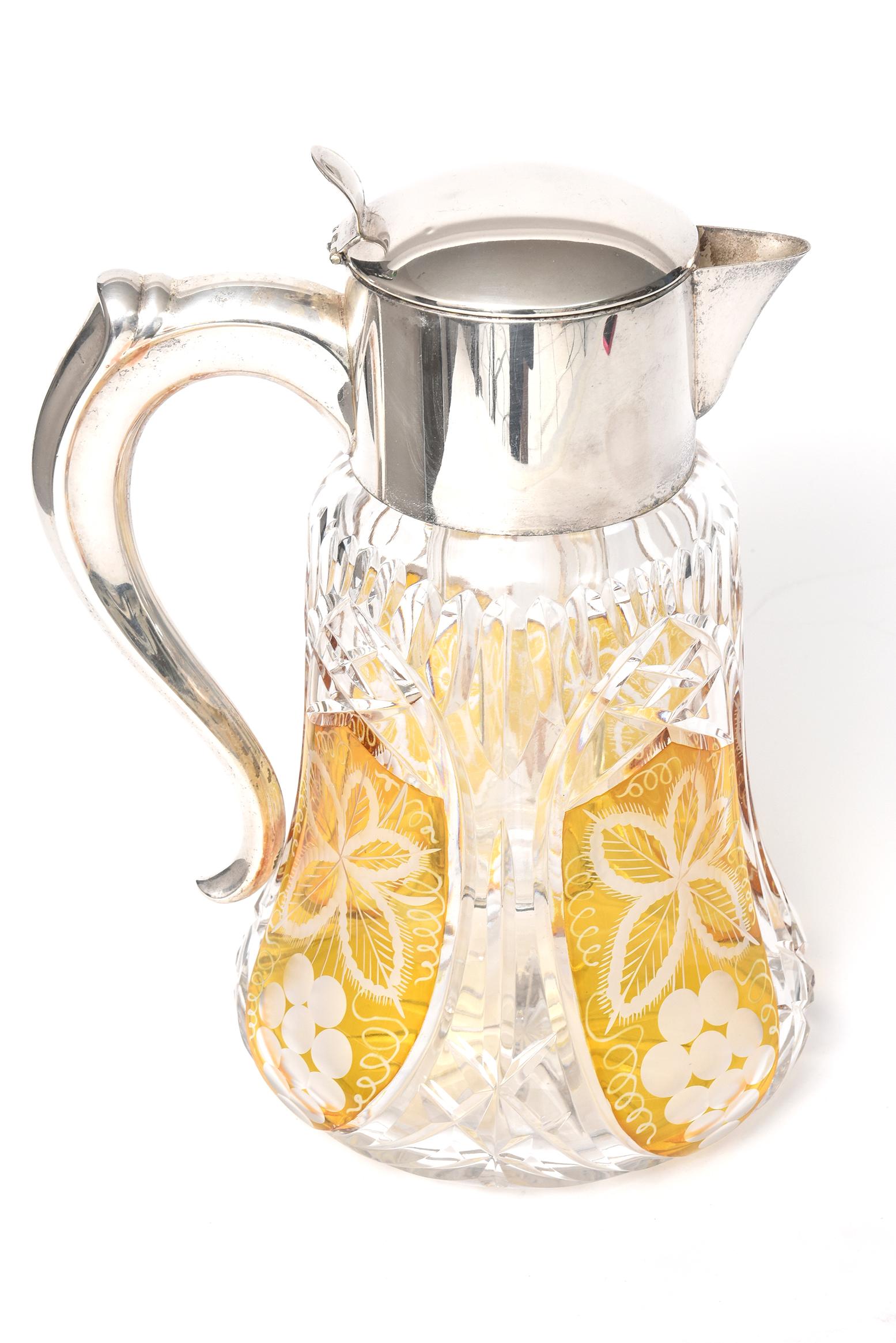 Impressive large Bohemian amber cut to clear glass pitcher featuring amber panels with grapes, leaf and vine motif. The handle, neck and spout are silver plate over copper. It has a silver plate top removable fitted glass tube which holds ice. The