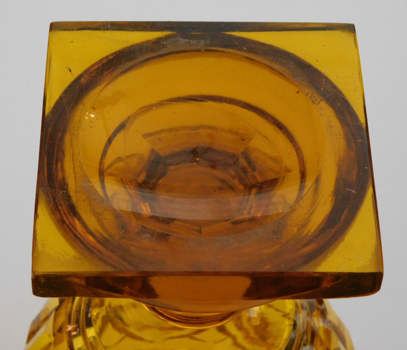 the all panel-cut jar with splayed cover topped with a faceted finial knob all resting on an ovoid body; unsigned; in the manner of Moser Glassworks.
