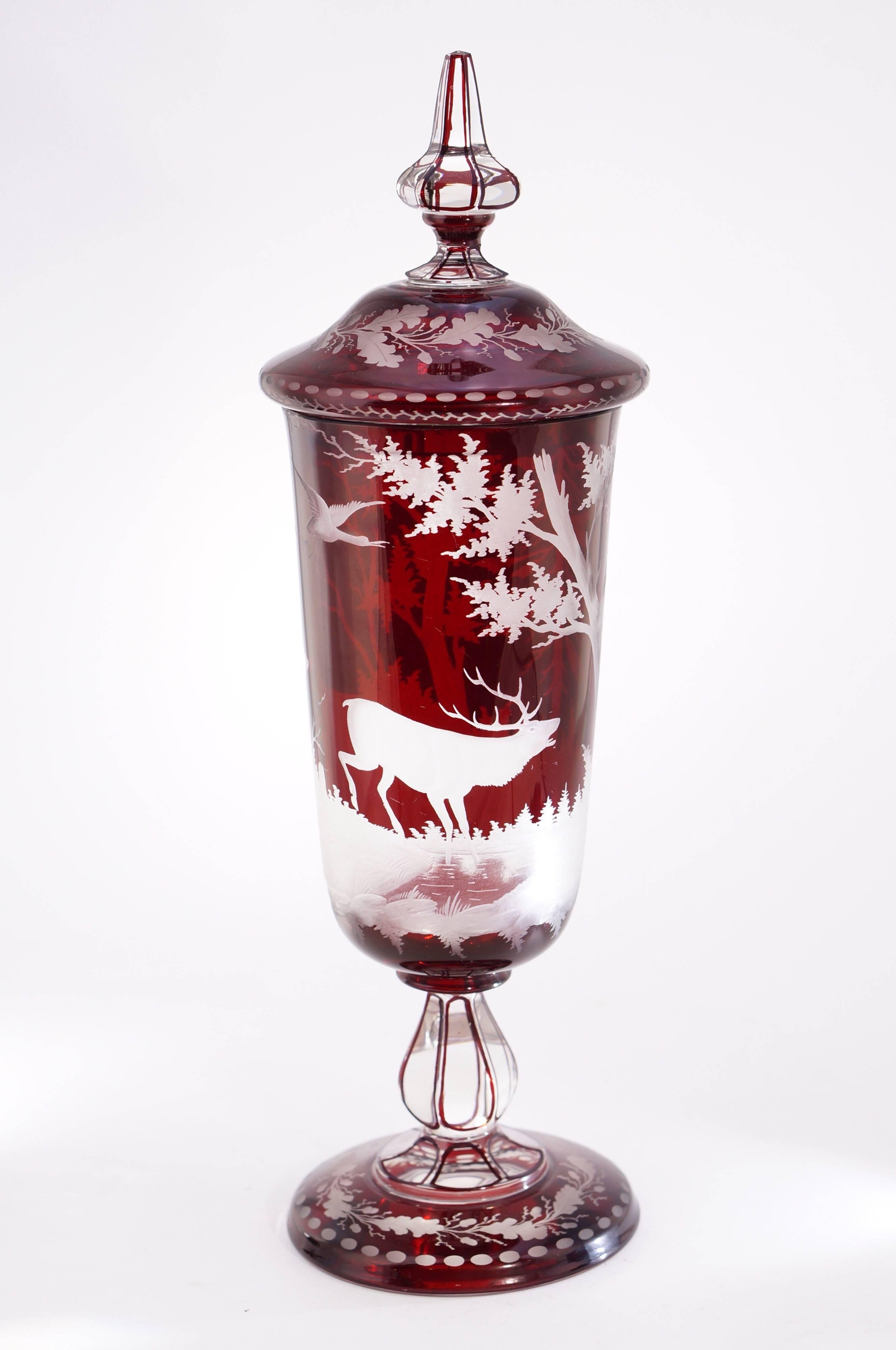 Bohemian ruby flash glass lidded vase with etched woods scene of trees, deer and birds, the lid and foot with acorns and leaves. 

circa 1880.
     
