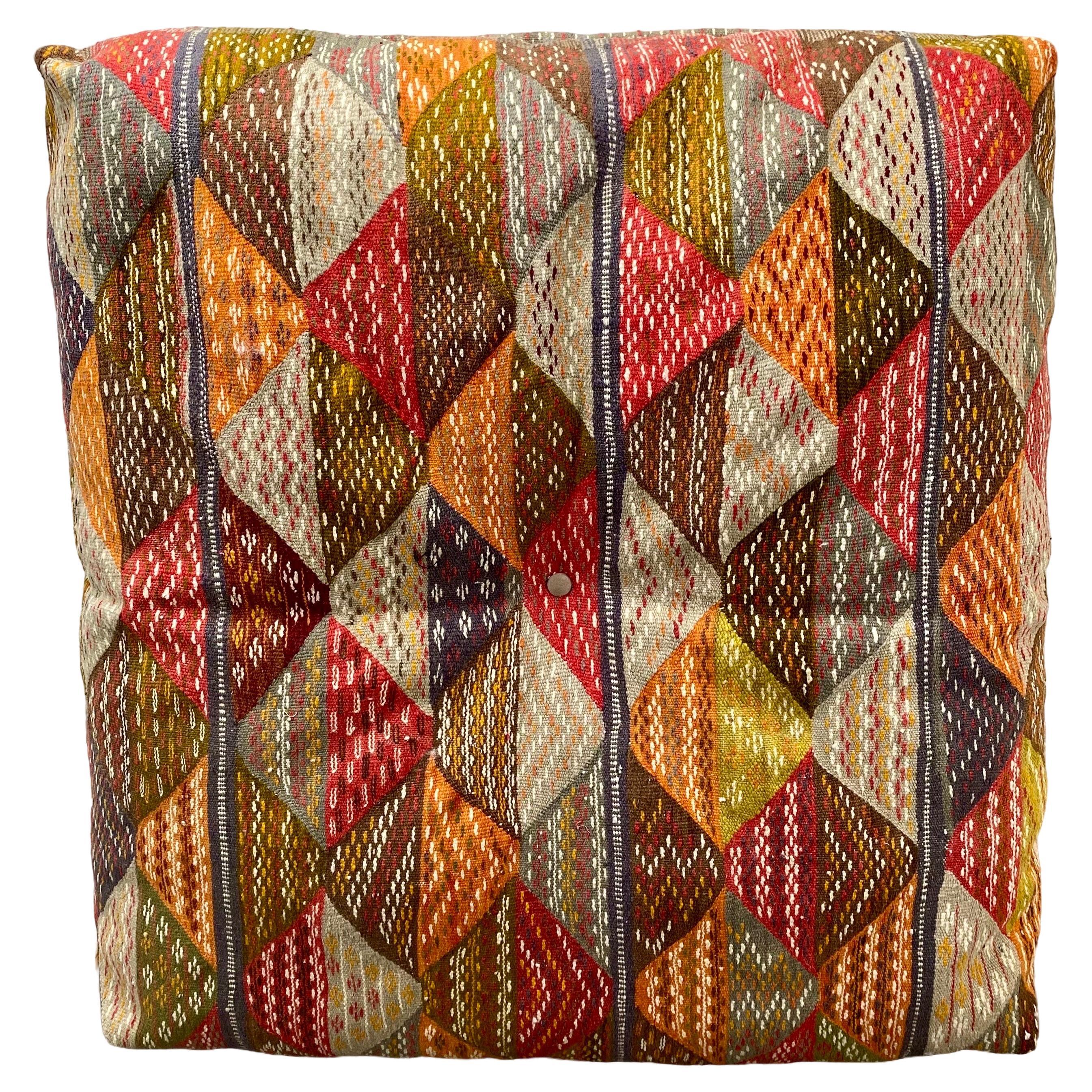 
A Boho Chic  oversized, large floor cushion, poof, or pillow crafted from a handwoven vintage Moroccan tribal flat-wave rug. This distinctive piece is meticulously fashioned from organic wool, imbued with natural dyes, resulting in an artisanal