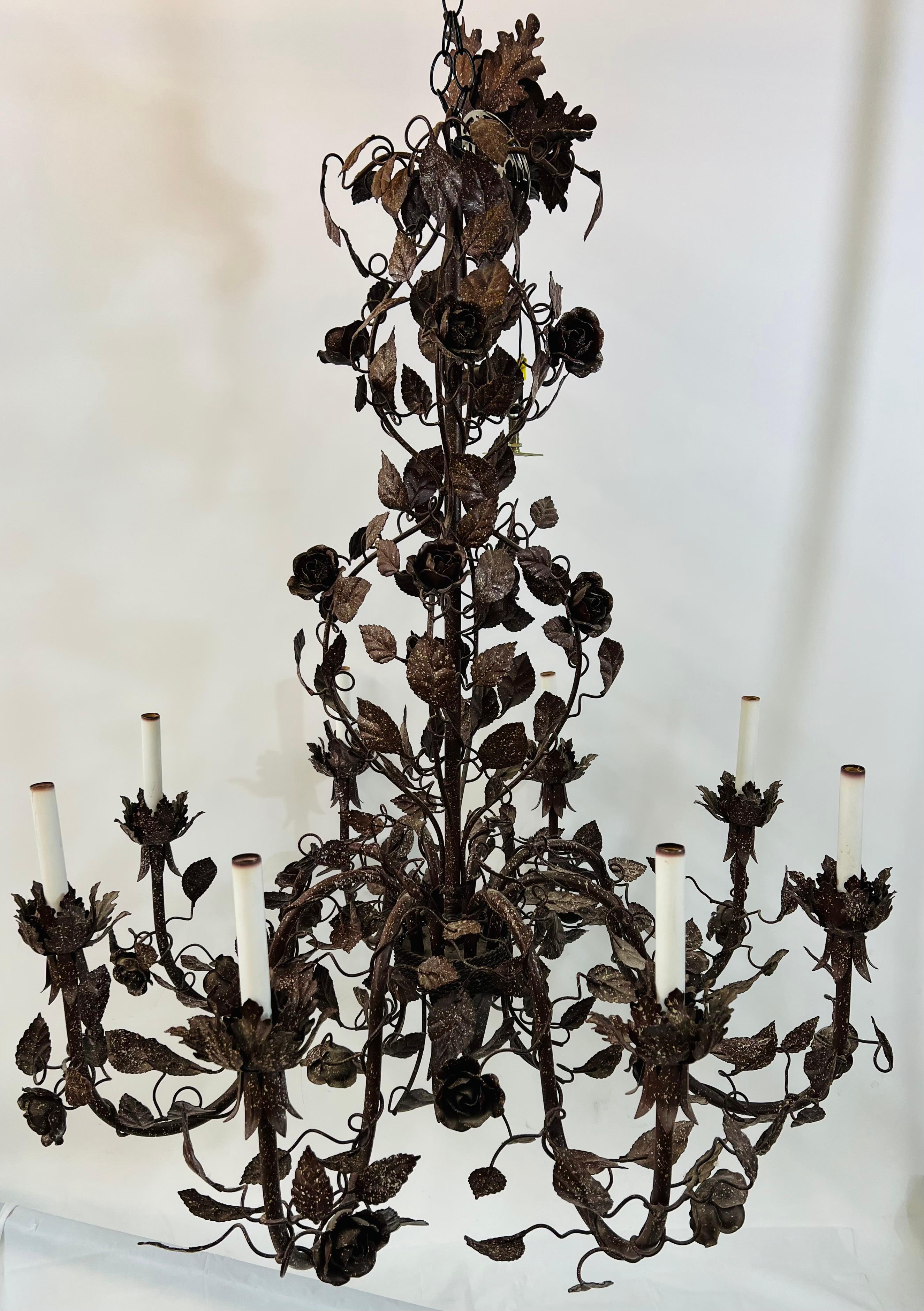 A large 1970's boho chic Italian tole metal chandelier. The hand tooled chandelier features flowers and leaves so beautifully arranged with leaves encircling the column of the chandelier. Hand-painted in dark brown with white spot design, the