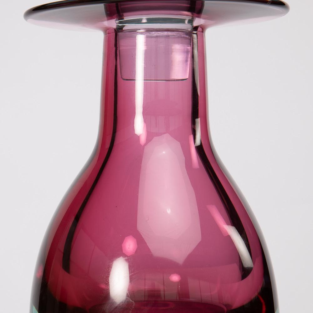 This large and massive blown Murano glass bottle with its stopper was designed by Mario Pinzoni in 1968 for Seguso vetri d´Arte in Murano, Italy. 
 The bottle was made using the sommerso method.  
Its body is dark pink and its bottom is blue. The