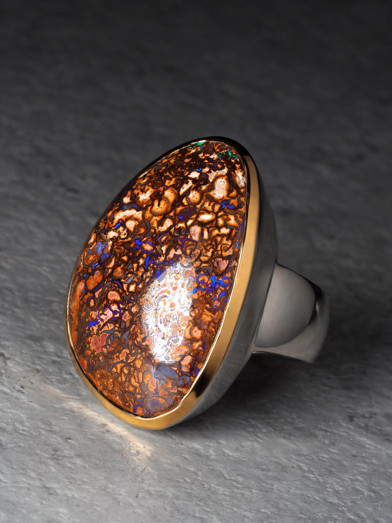Este excepcional anillo de Ópalo Koroit de Boulder es una pieza escultural que captura el dramático arte geológico por el que es famosa la región. El gran ópalo de 9 quilates muestra una intrincada matriz natural: una red de brillantes formaciones