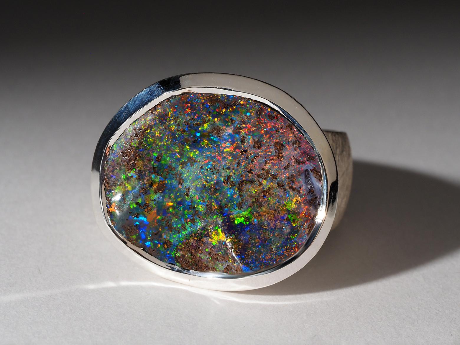 Abbandonati alla squisita bellezza di questo pezzo unico: un anello in argento sterling, meticolosamente realizzato con una finitura opaca e con un'opale australiana Boulder cabochon ovale da 8,45 carati. L'opale affascina con la sua straordinaria