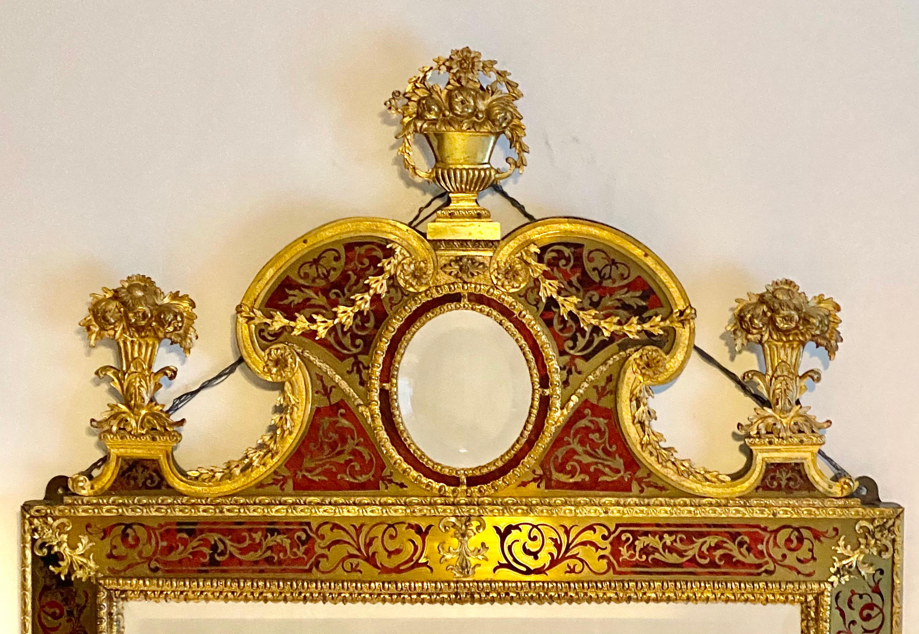 An attractive high quality 19th century boulle upright wall mirror, the frieze inset small oval mirrored centre with moulded scroll border and three cast gilt metal floral urns above, the central oval bevelled plate within a frame with satyr mask