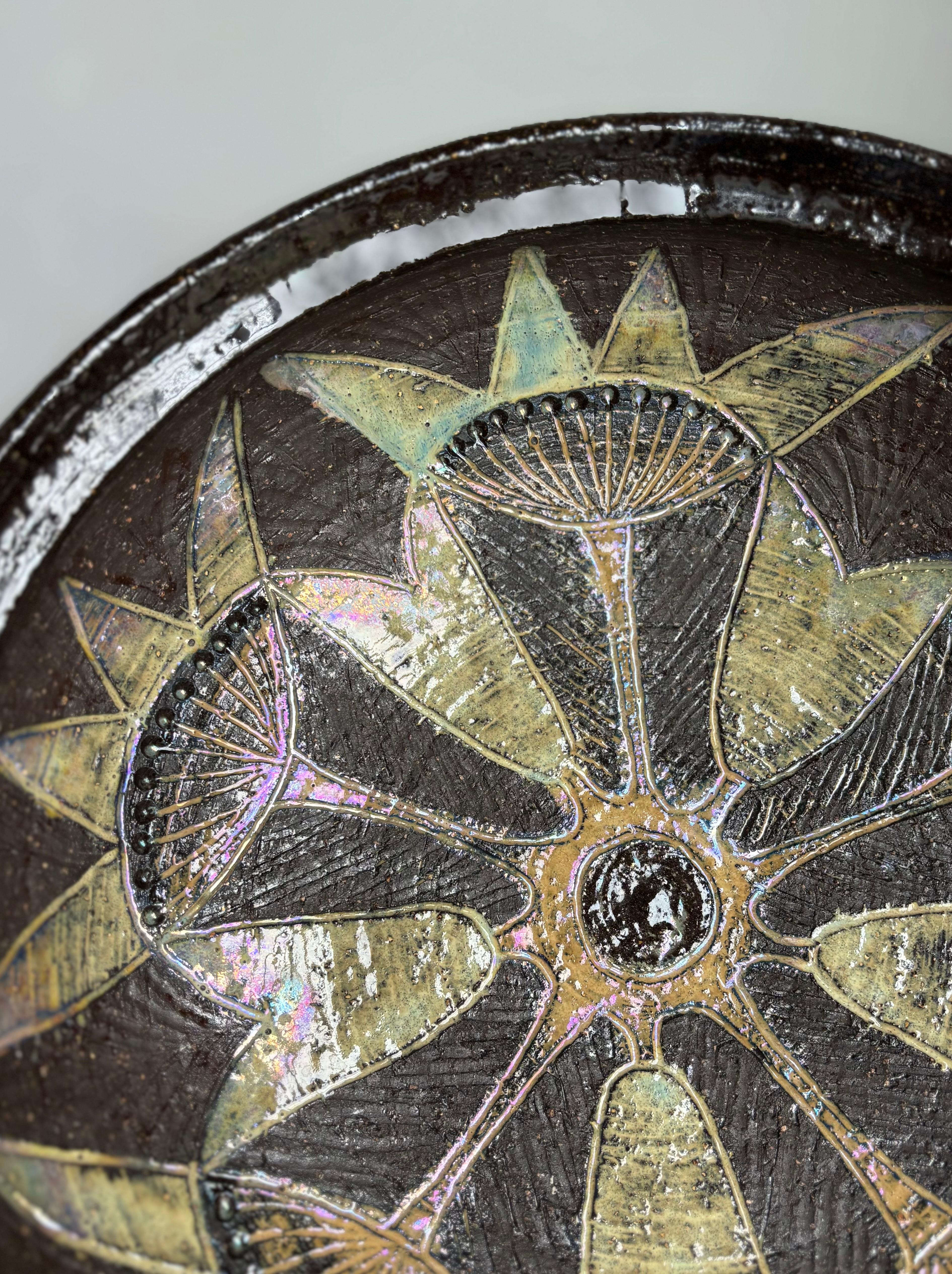 Swedish modern stoneware bowl by ceramic artist Elsi Margareta Bourelius (1909-2001). Raw chocolate brown chamotte clay with shiny glazed stylized floral decor in dusty yellow, light blue and dark brown colors. 
Signed by the artist. 
Beautiful