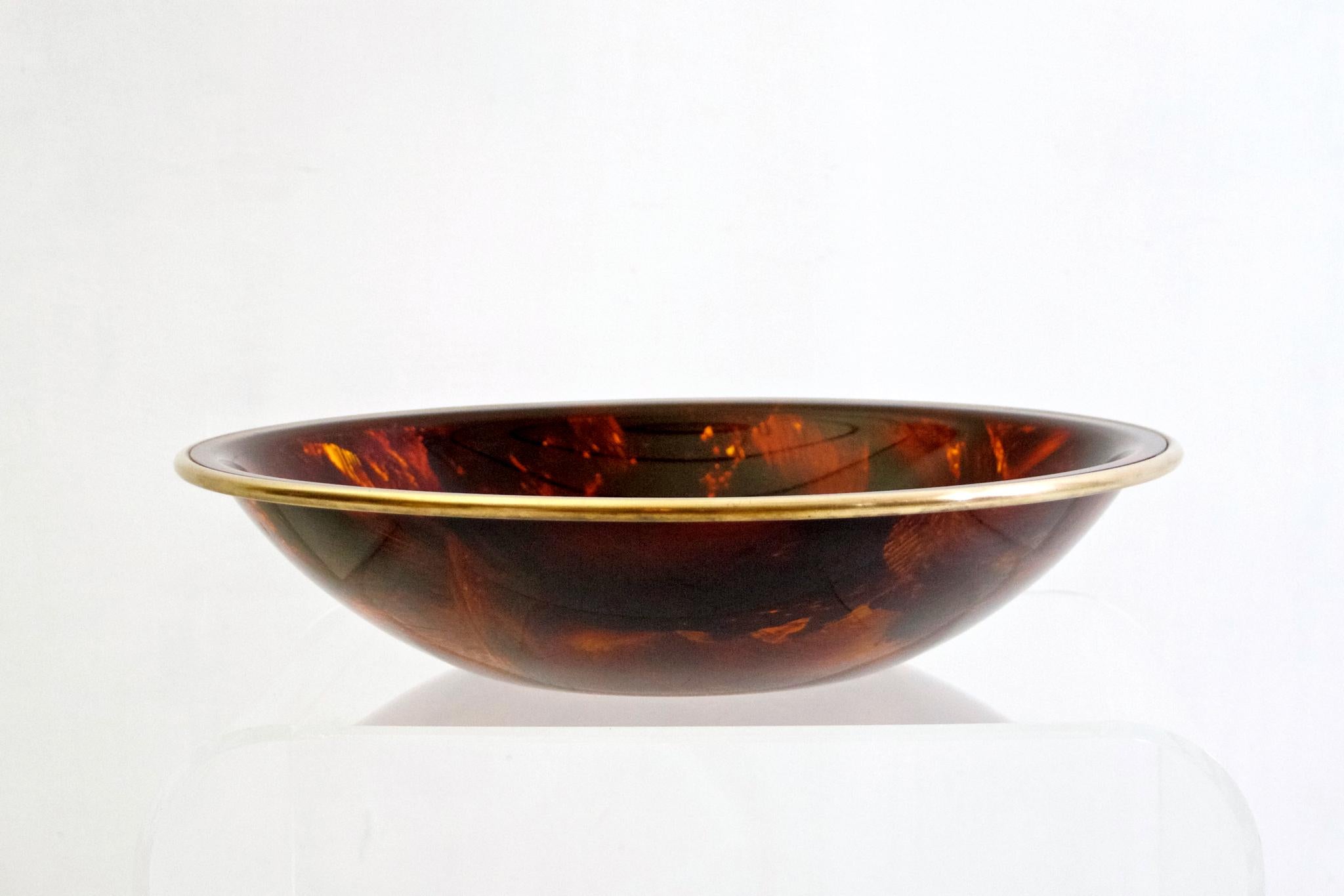 A large vintage bowl in tortoise Lucite with a brass rim made in Italy during the 1970s.
  
