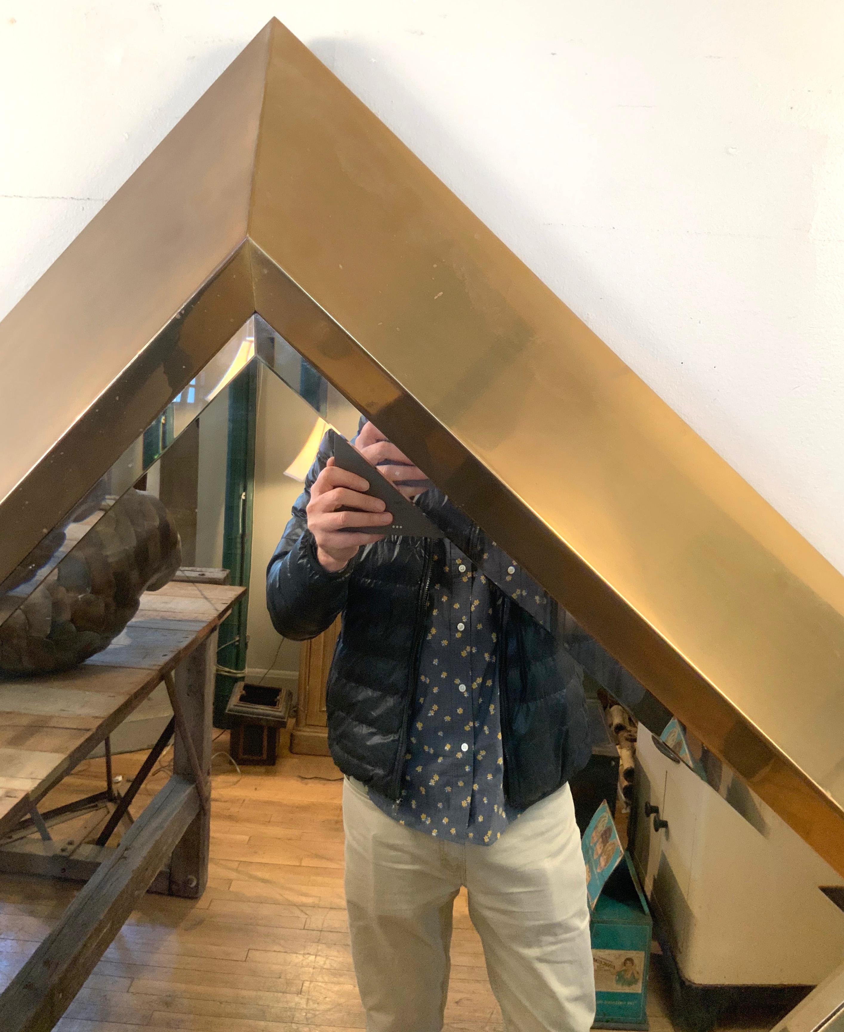 A large and stunning 1970s wall mirror with a deep and wide dramatic brass frame in diamond form, with a beveled mirror inset. Designed by Marcello Mioni. The brass has some finish loss and slight discolorations, but no dents or scratches. The scale