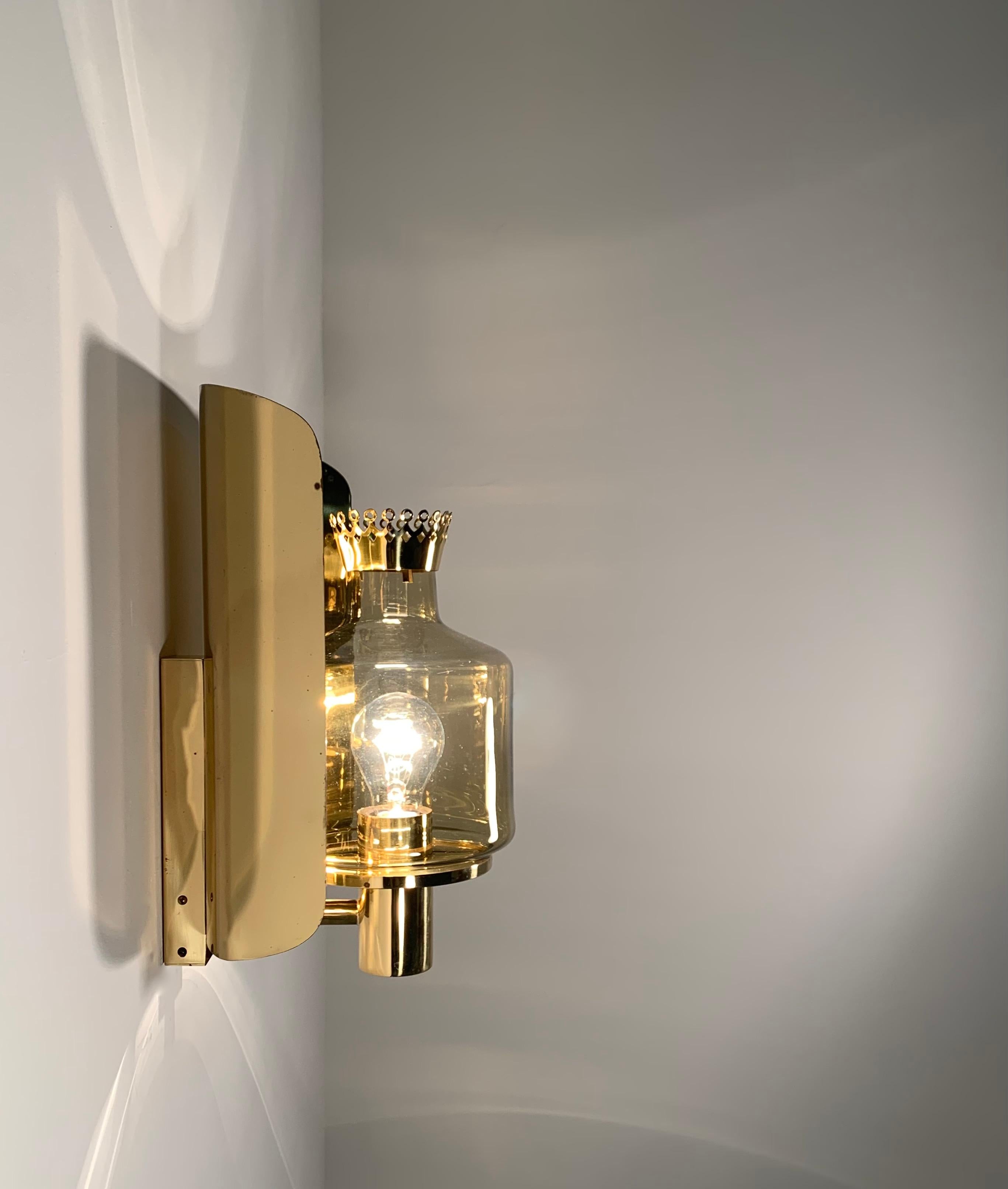 Large impressive 'crown' wall lamp by Hans Agne Jakobsson, model V222.  
Brass wall sconce with amber glass shade equipped with a crown ornament - which is almost always missing. The lamp can also be installed without this crown ornament as shown on