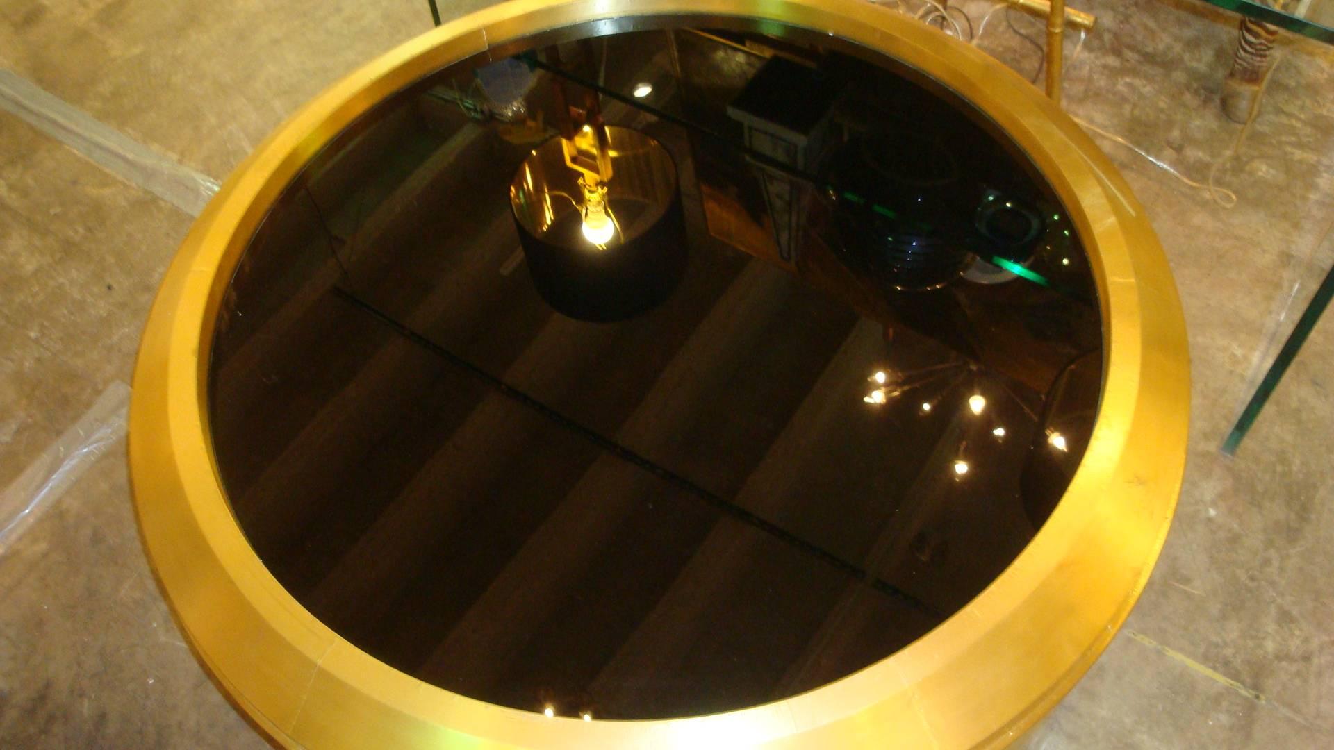 This is a large round glass and unlacquered brass coffee table. It has some distressed areas to brass to give that industrial feel.