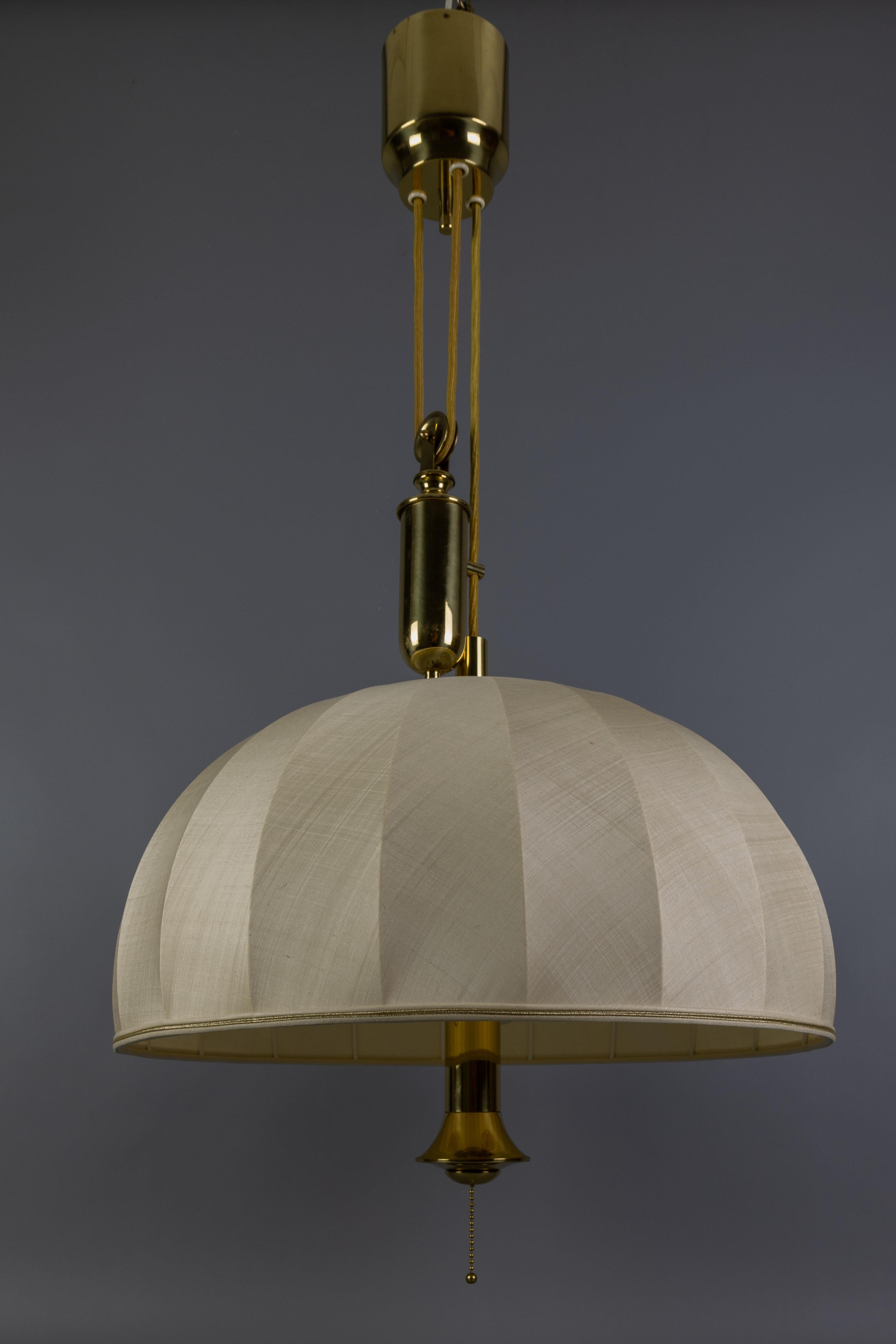 Grande lampada a sospensione a cinque luci regolabile in altezza in ottone con paralume in tessuto e contrappeso, Germania, anni '70 circa.
Realizzata in stile The Scandinavian Modern, questa imponente lampada a sospensione presenta un ampio