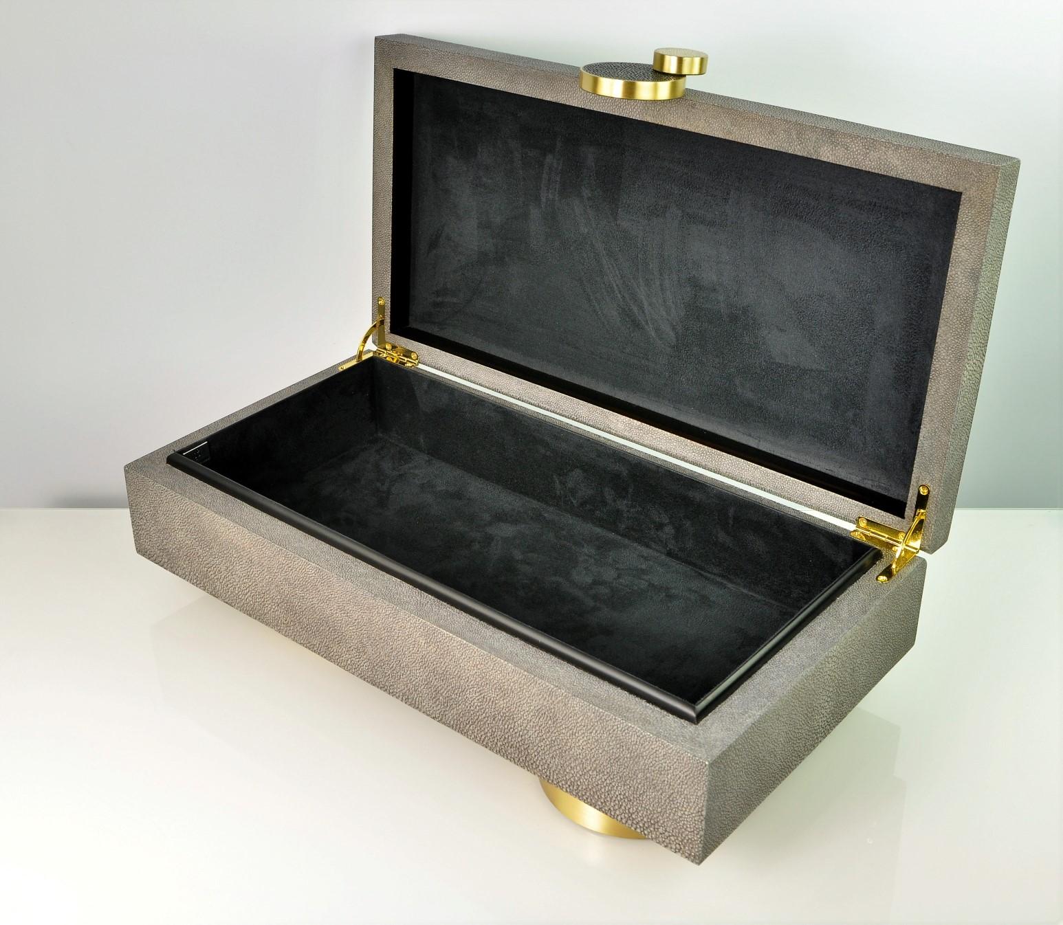 This elegant box is made of shagreen with a beautiful circular decor with brass trims on the front.
It is mounted on two circular brass feet.
The box is hinged with a black microsuede interior. 

Perfect to tidy up your remote controls on your