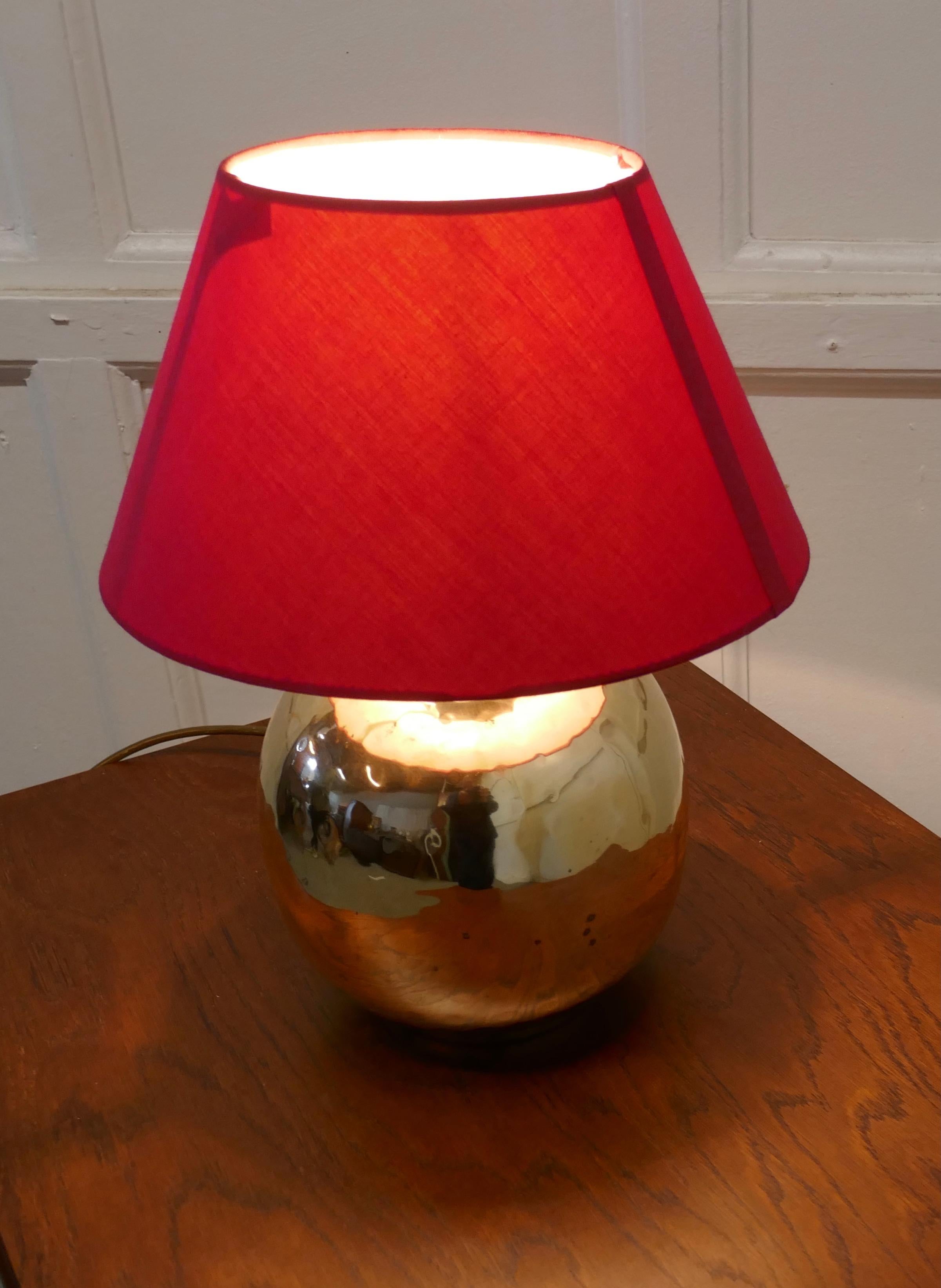 Large brass ball table lamp 

This is an unusual Lamp has a smooth globe shape and a red lampshade 
The lamp is fully wired and in good condition, a statement piece in any room
The lamp is 15” tall, 12” in diameter and the shade is 20” in