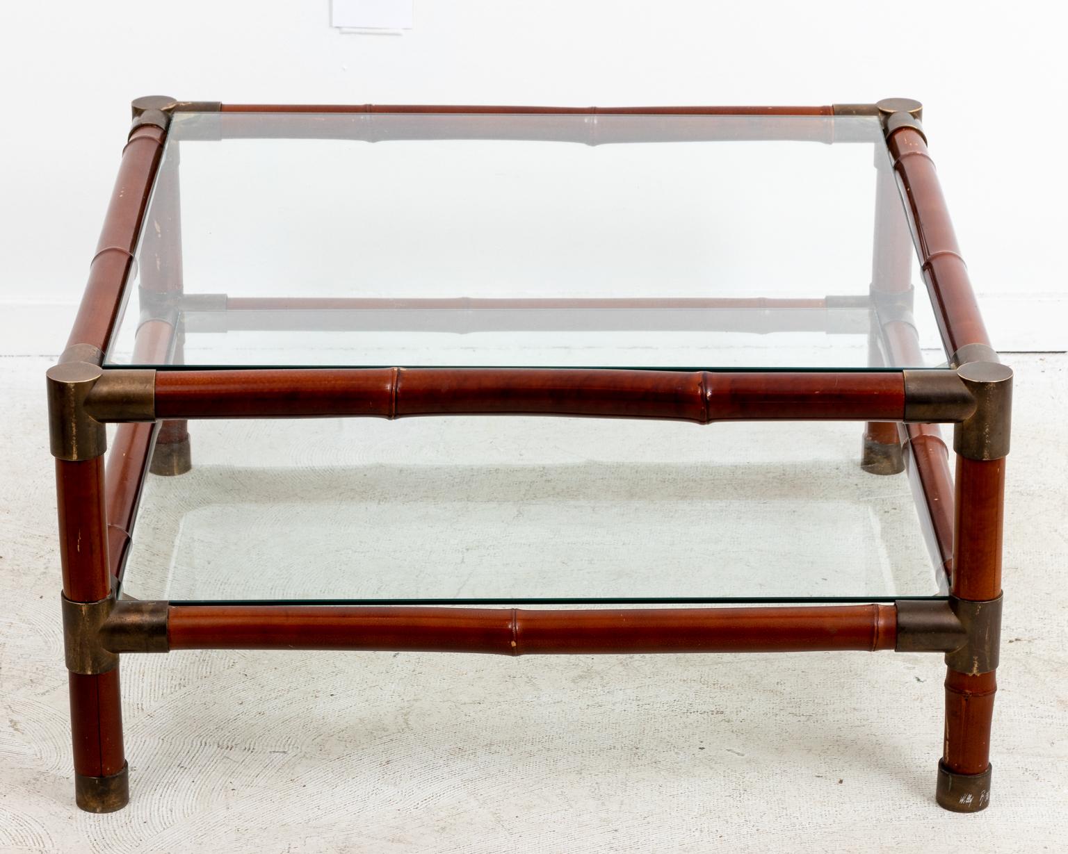 Large brass banded two tier square coffee table with glass top by Willy Rizzo. Please note of wear consistent with age including chips and minor finish loss to the faux bamboo finished frame along with minor patina to the brass bands.