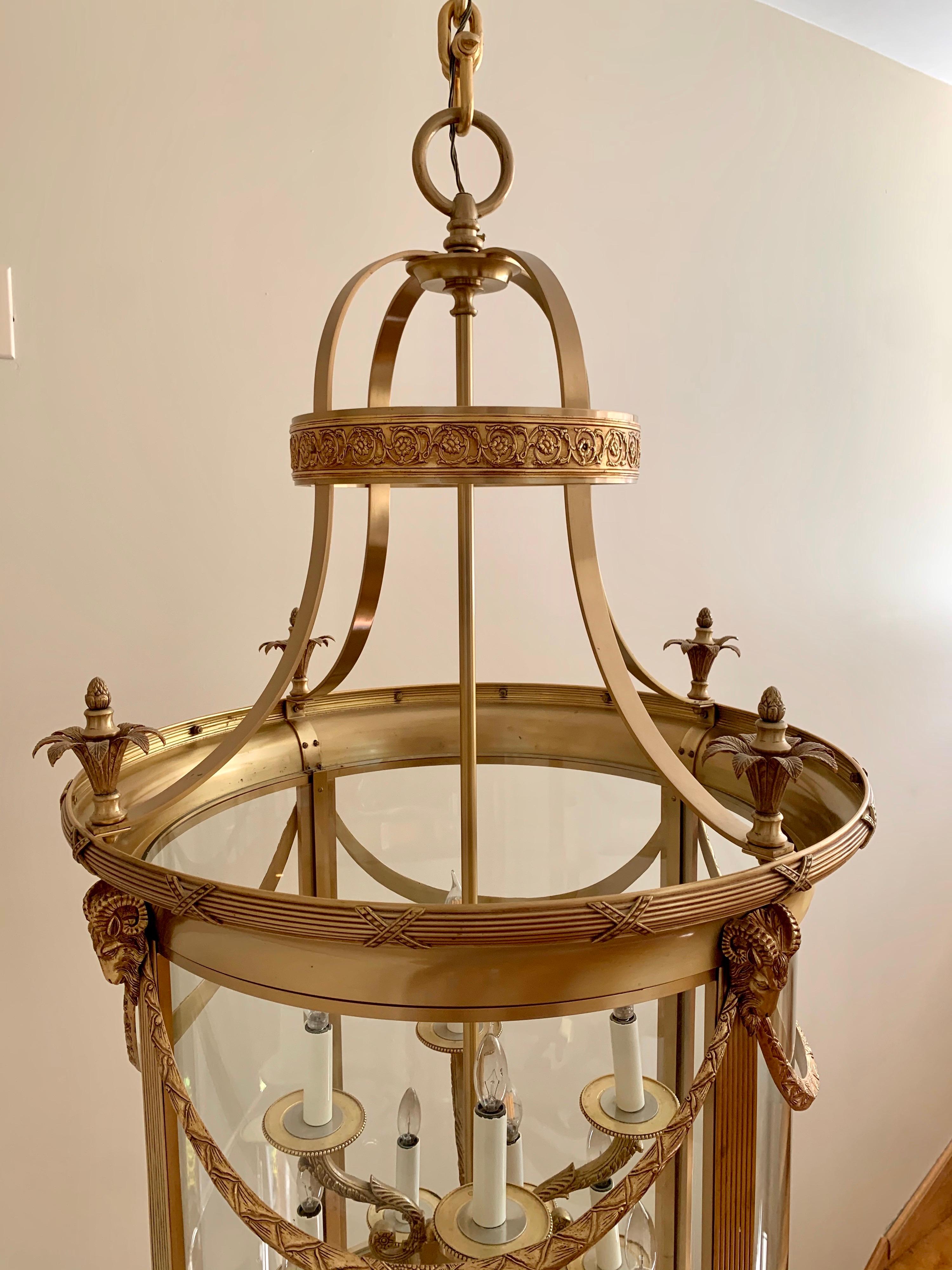Large cylindrical 12-light brass chandelier features ornate swags and floral detail accented with ram heads. Can be hung in a two story foyer or staircase. Features a thick brass adjustable chain. This is a large piece that is 54