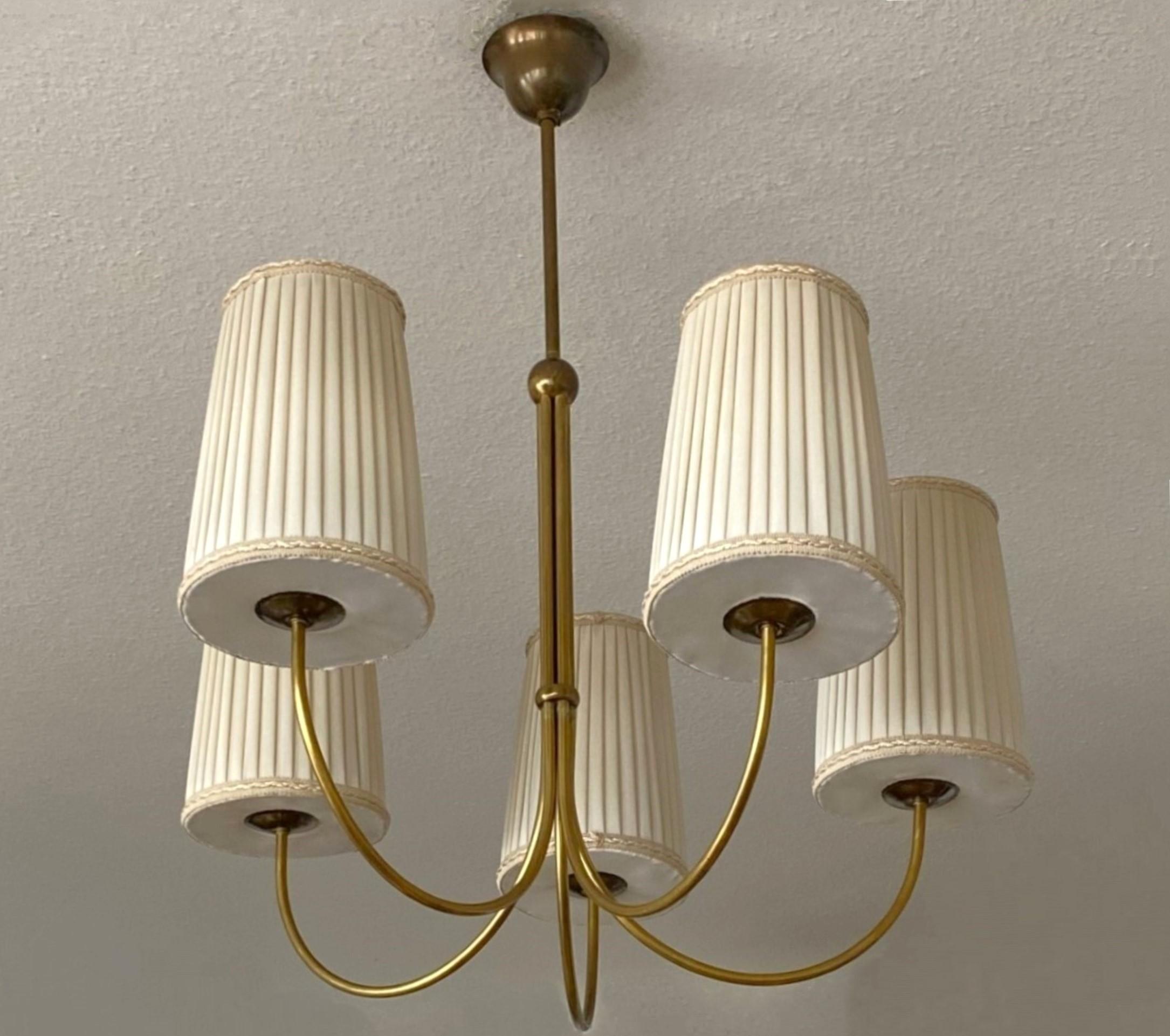 A large brass five-light chandelier manufactured in Austria in the 1950's designed by Josef Frank for Kalmar. Five curved brass lamp arms with the five original pleated silk lamp shades. Under each shade one E27 brass socket for medium or large