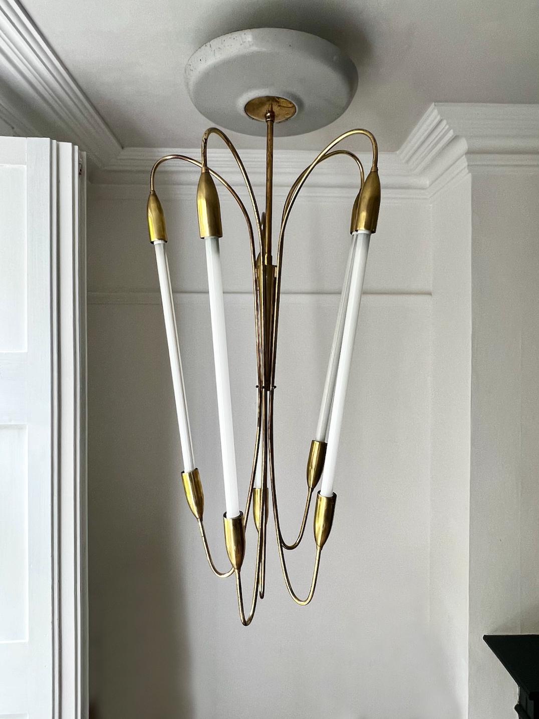 Un imponente lampadario di grandi dimensioni con struttura asimmetrica in ottone e grande baldacchino da soffitto in stile art deco o Bauhaus. Il disegno è attribuito a Kaiser of Germany, probabilmente tra gli anni '30 e '50 del secolo scorso. Luci