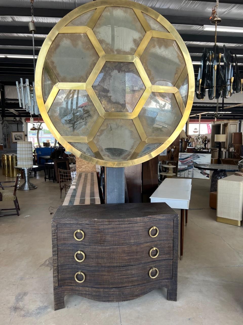 A large brass convex mirror with an antique finish is a round mirror with a thick border of textured of brass and a polished brass edge. The mirror is compose of seven convex, meaning it has a curved surface that bulges outward with frame that is 2