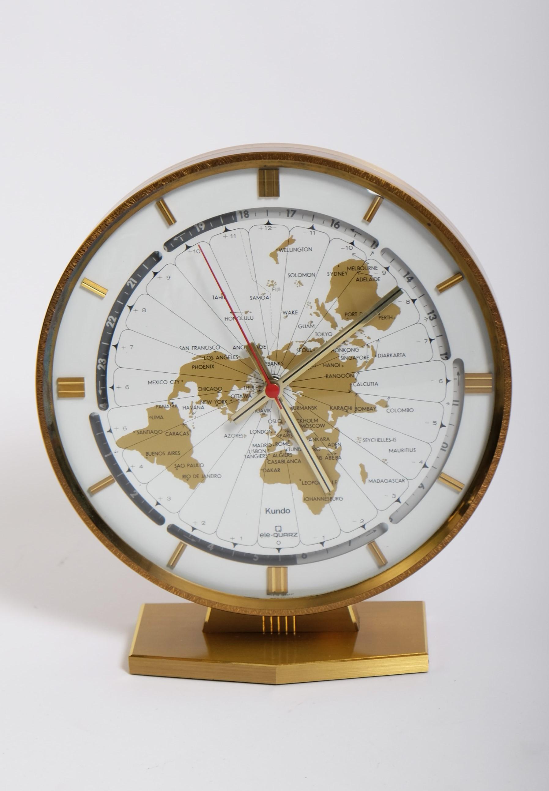 Large modernist brass table world time clock by Kundo / Kieninger & Obergfell, West Germany circa 1970s.

Beautiful clock with a large 9-inch round dial in white with a gold world map design and world time zones. The heavy case and base are made of