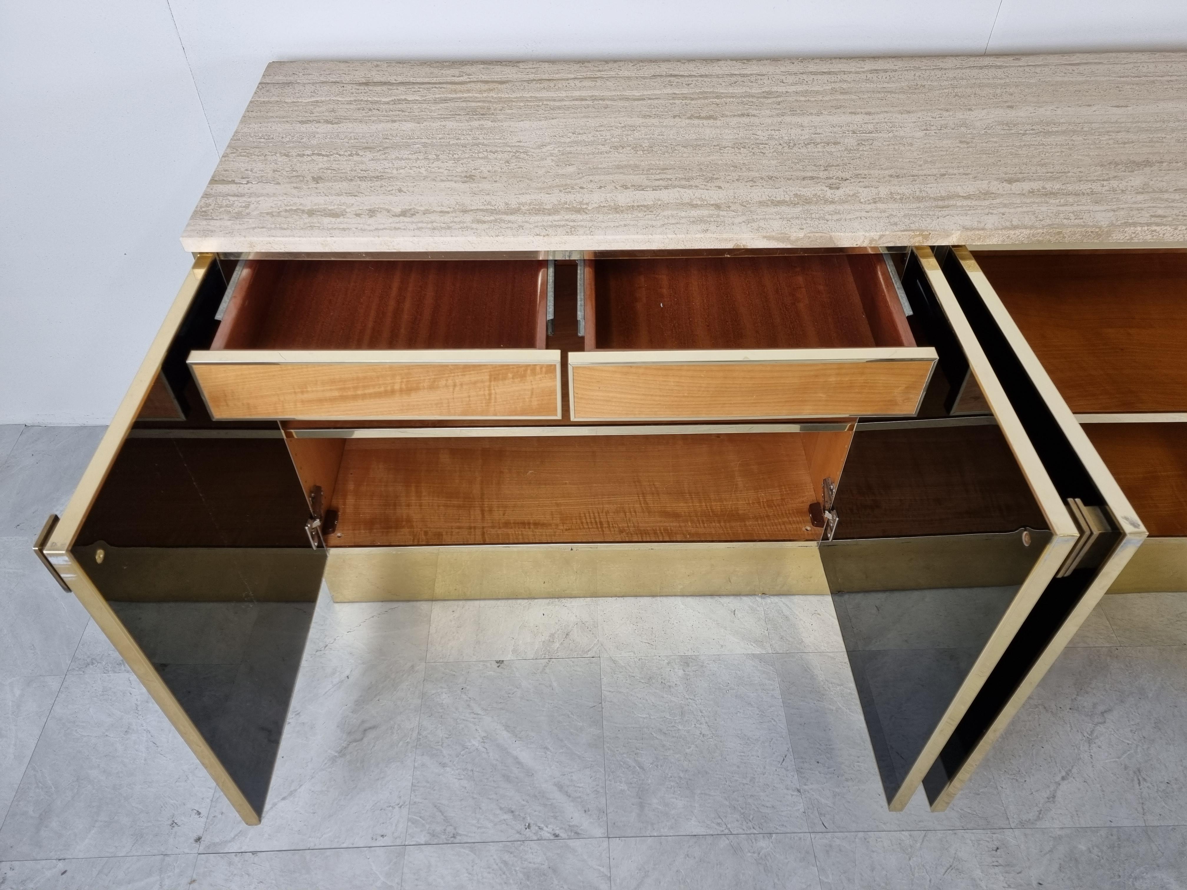 Luxurious seventies glamour sideboard by Maison Jansen consitsing of black lacquer panels, brass and a travertine top.

The use of different high quality materials makes this piece a real eye catcher.

It also provides a lot of storage