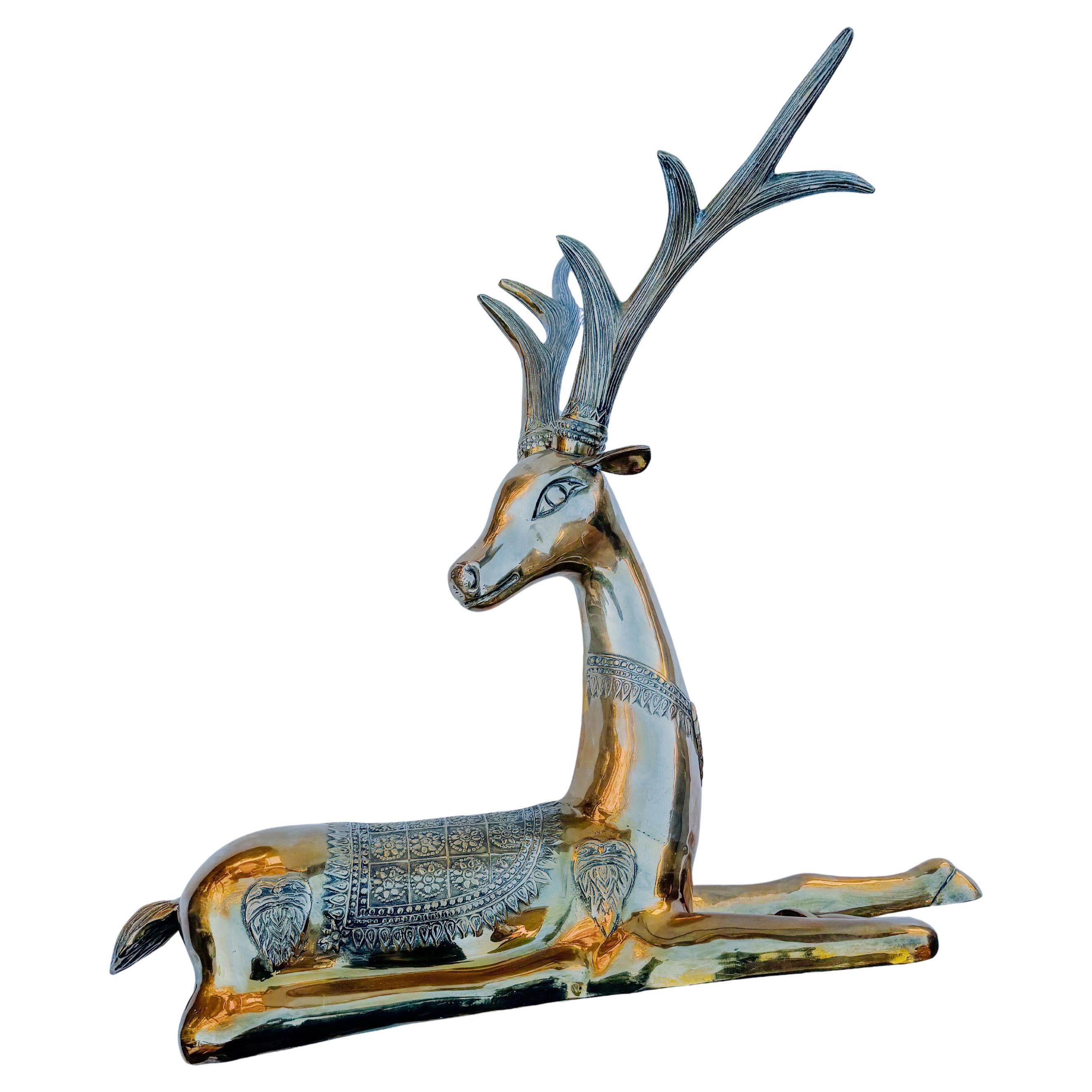 This striking large cast brass recumbent deer sculpture is a statement piece, perfect for adding a touch of elegance to your holiday decor. Attributed to Sarreid, this sculpture features exquisite detailing on its antlers and saddle, showcasing