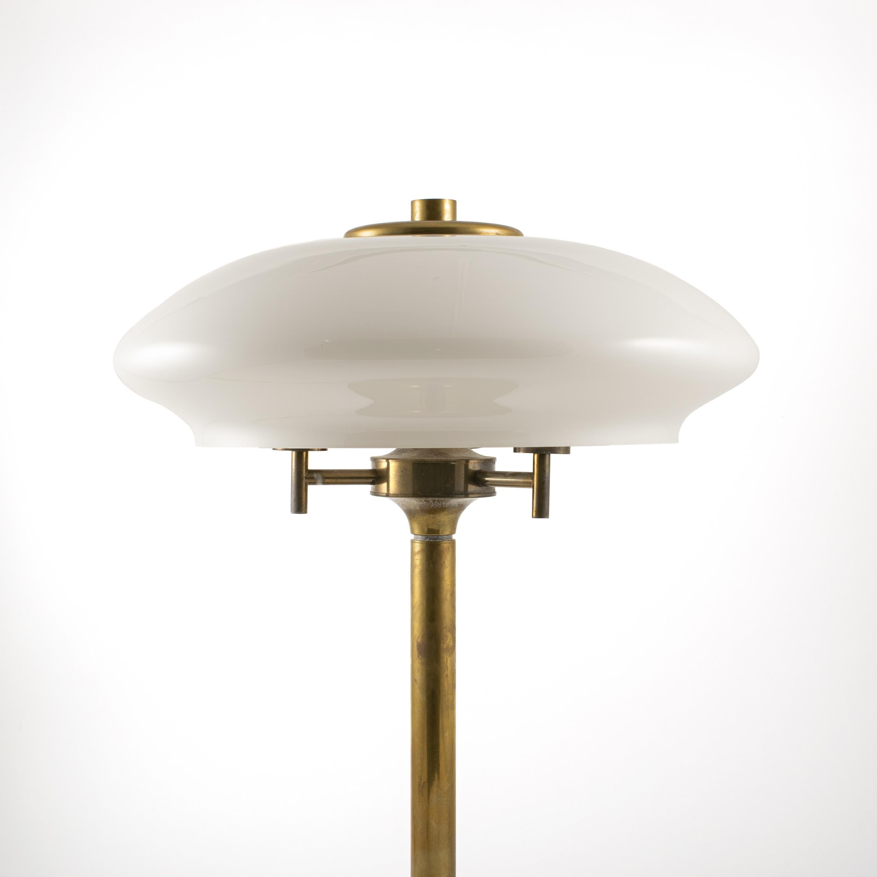 Large brass table lamp with shade of opal glass. Three light sources.
Denmark, 1950s.
The lamp is in original and untouched condition.

Base diameter 30 cm.