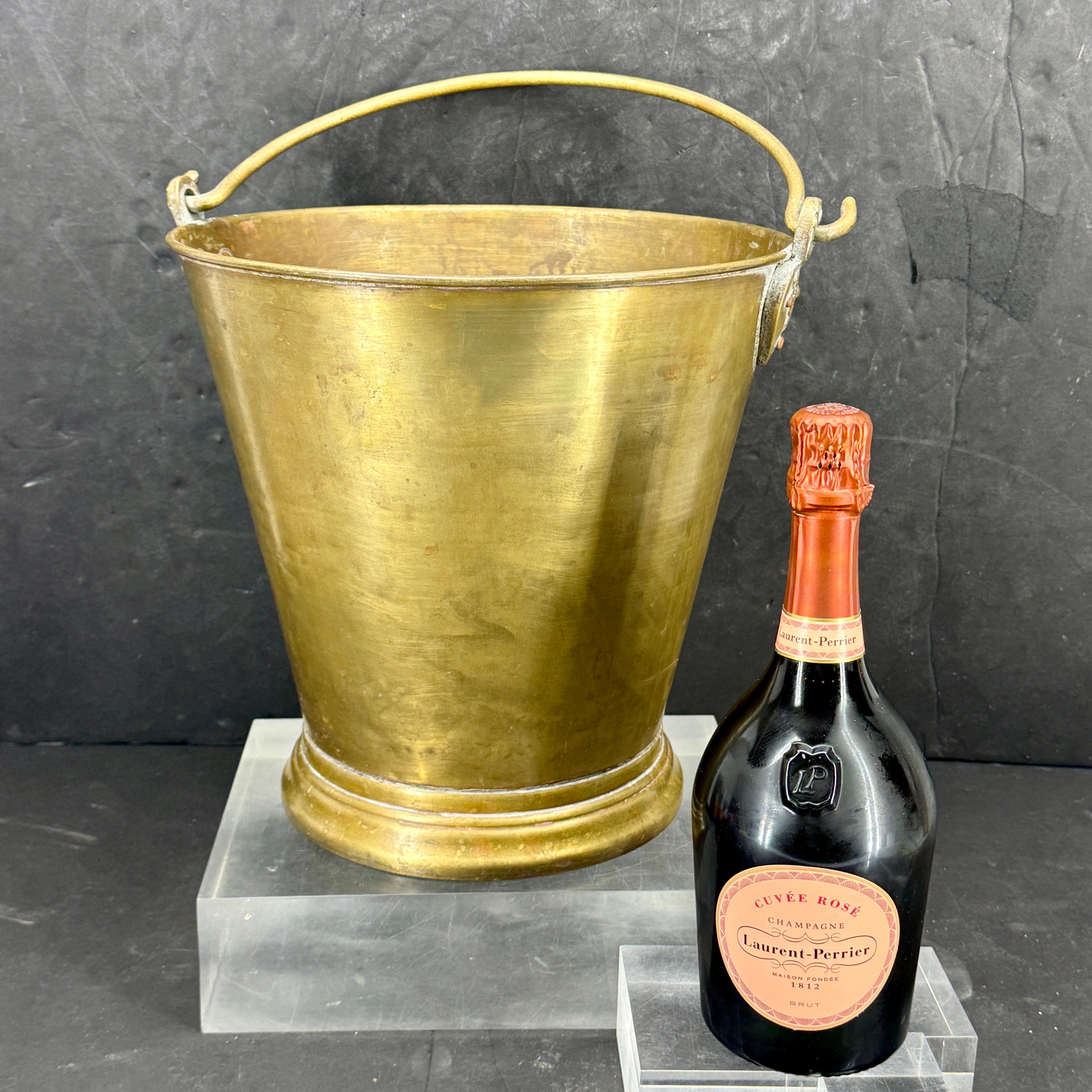 Questo imponente secchiello per vino o champagne è caratterizzato da una finitura in ottone. Come si vede in tutta Europa, questo secchio in fusione è in grado di elevare qualsiasi occasione. La patina naturale di un pezzo crea un look distintamente